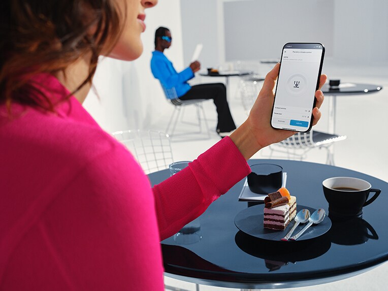 Eine Frau hält ihr Handy in der Hand und nutzt dabei die Mercedes me App.