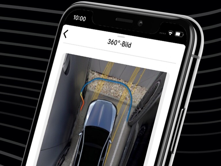 Mit der Mercedes-Benz Remote Park-Assistent App und der 360°-Ansicht auf einem Smartphone wird ein Mercedes-Benz bequem in eine enge Parklücke gelenkt.