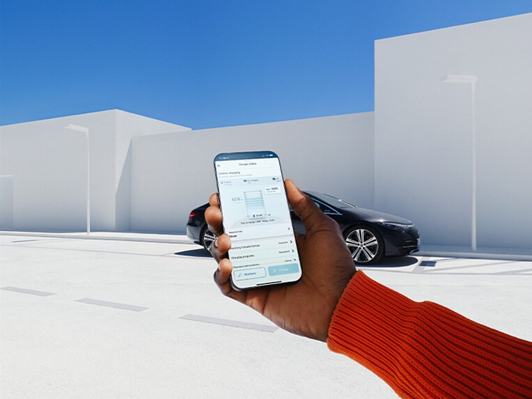 Eine Frau nutzt die Mercedes-Benz App auf ihrem Smartphone, um sich mit Ihrem Mercedes-Benz zu verbinden.