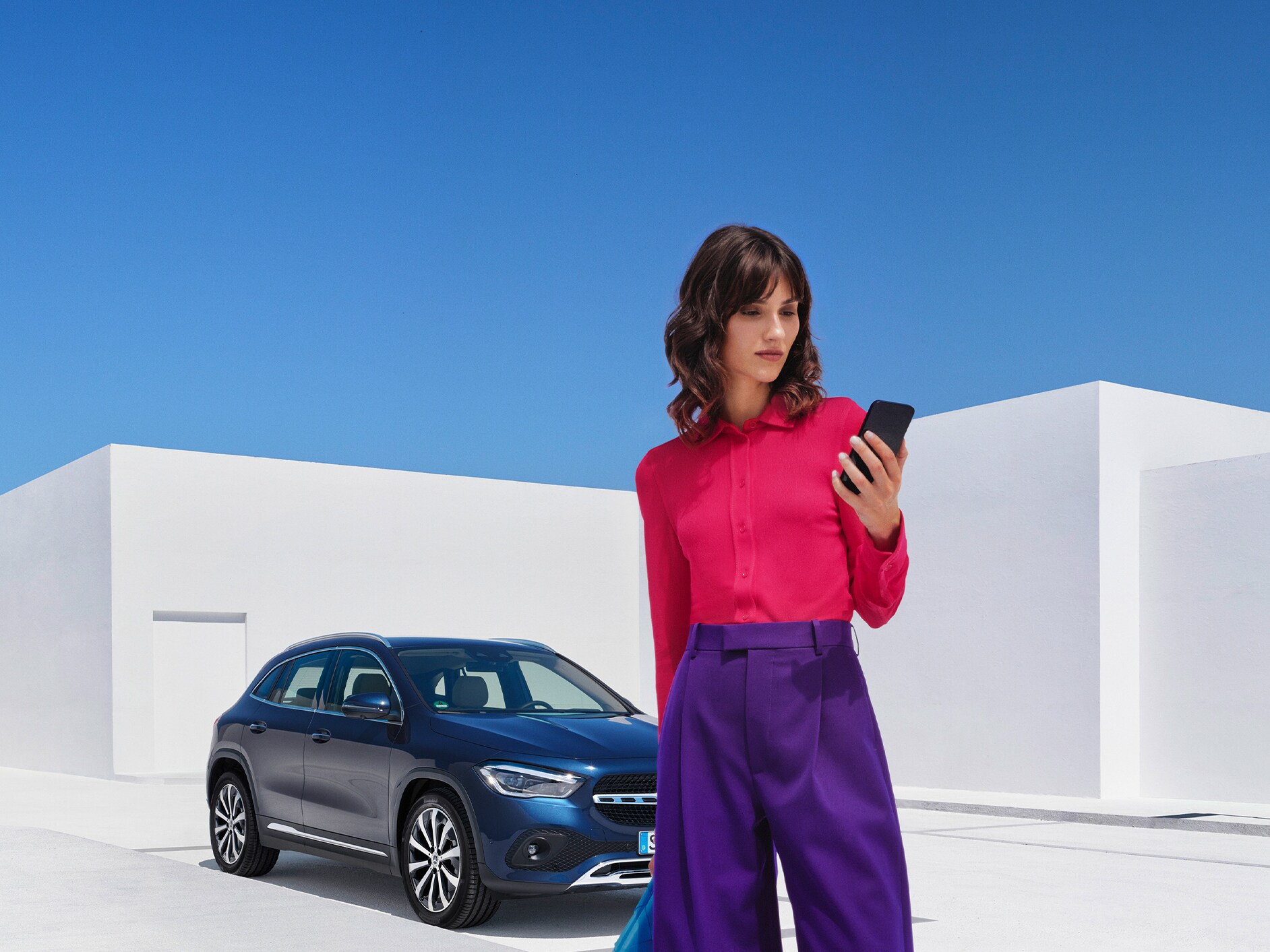 Eine Frau stellt per Mercedes-Benz App auf ihrem Smartphone eine Verbindung mit ihrem Mercedes-Benz her.