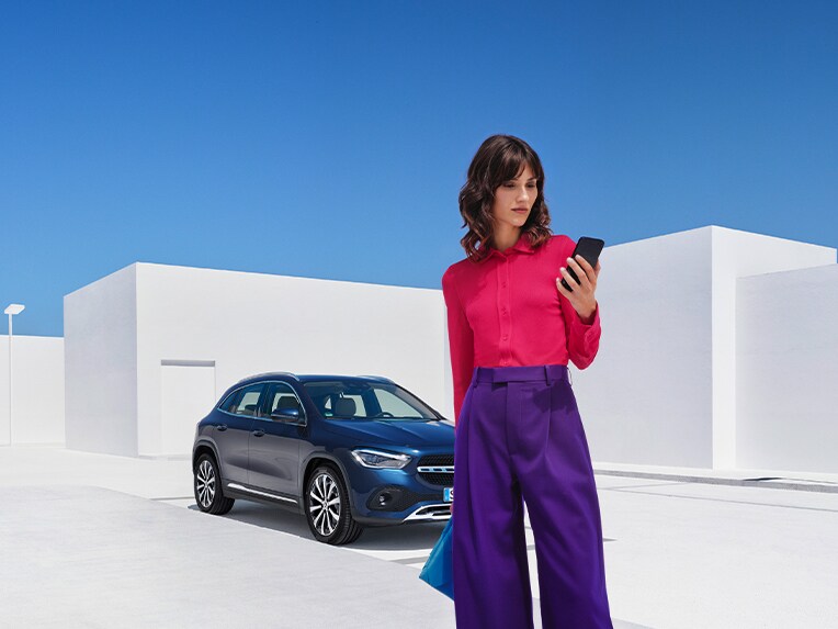 Eine Frau stellt per Mercedes-Benz App auf ihrem Smartphone eine Verbindung mit ihrem Mercedes-Benz her.