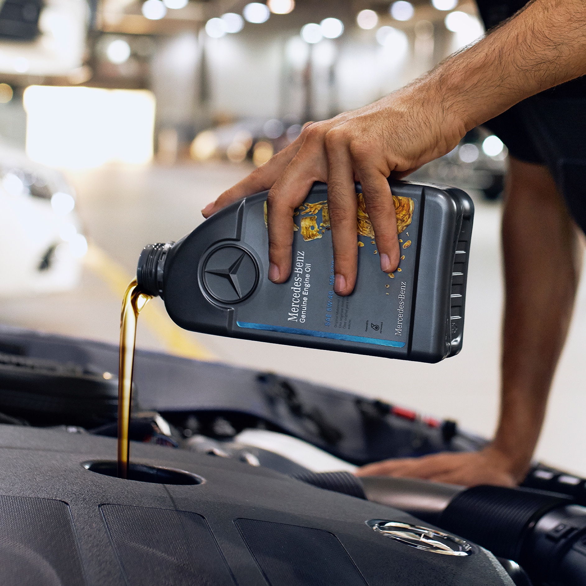 Motoröl | Mercedes-Benz Eine Person, die Motoröl in das Mercedes-Benz Fahrzeug einfüllt.