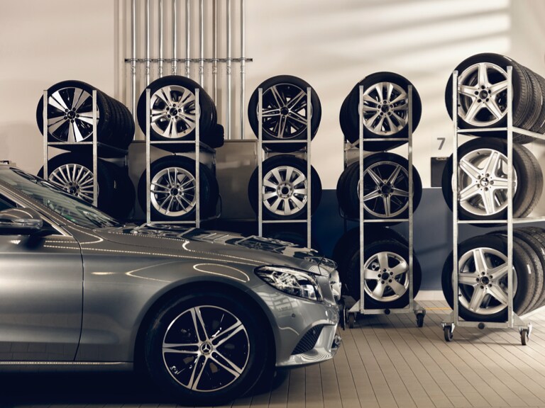 Ein Mercedes-Benz steht vor einigen Regalen mit eingelagerten Rädern.