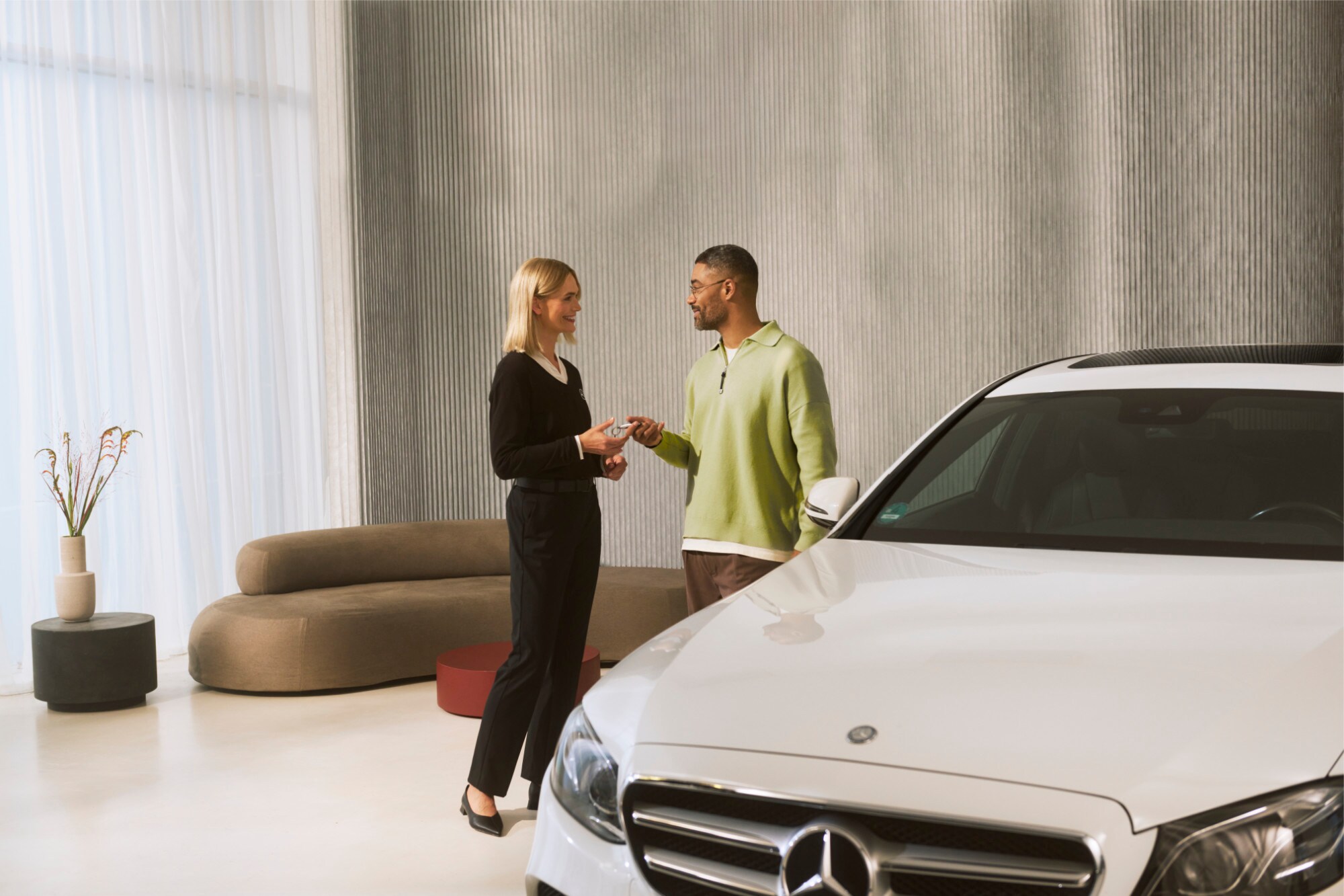Ein Mercedes-Benz Berater bei der Übergabe der Fahrzeugschlüssel an einen Kunden.