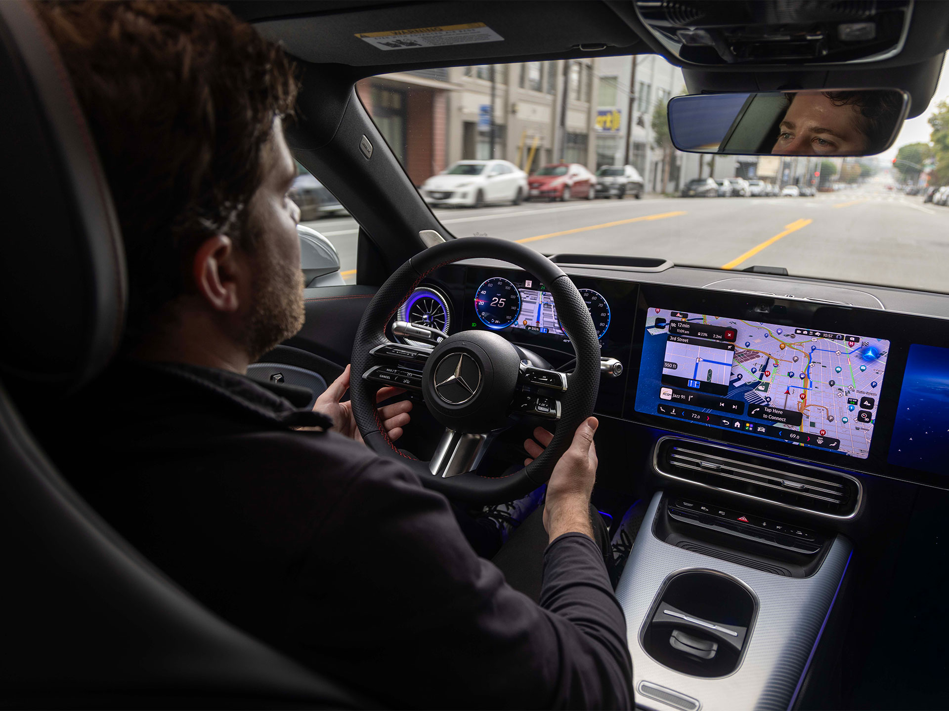 Automatisiertes Fahren & Assistenzsysteme | Mercedes-Benz Ein mann sitzt im Cockpit eines Mercedes-Benz und fährt auf einer Straße mit gelben Markierungen.