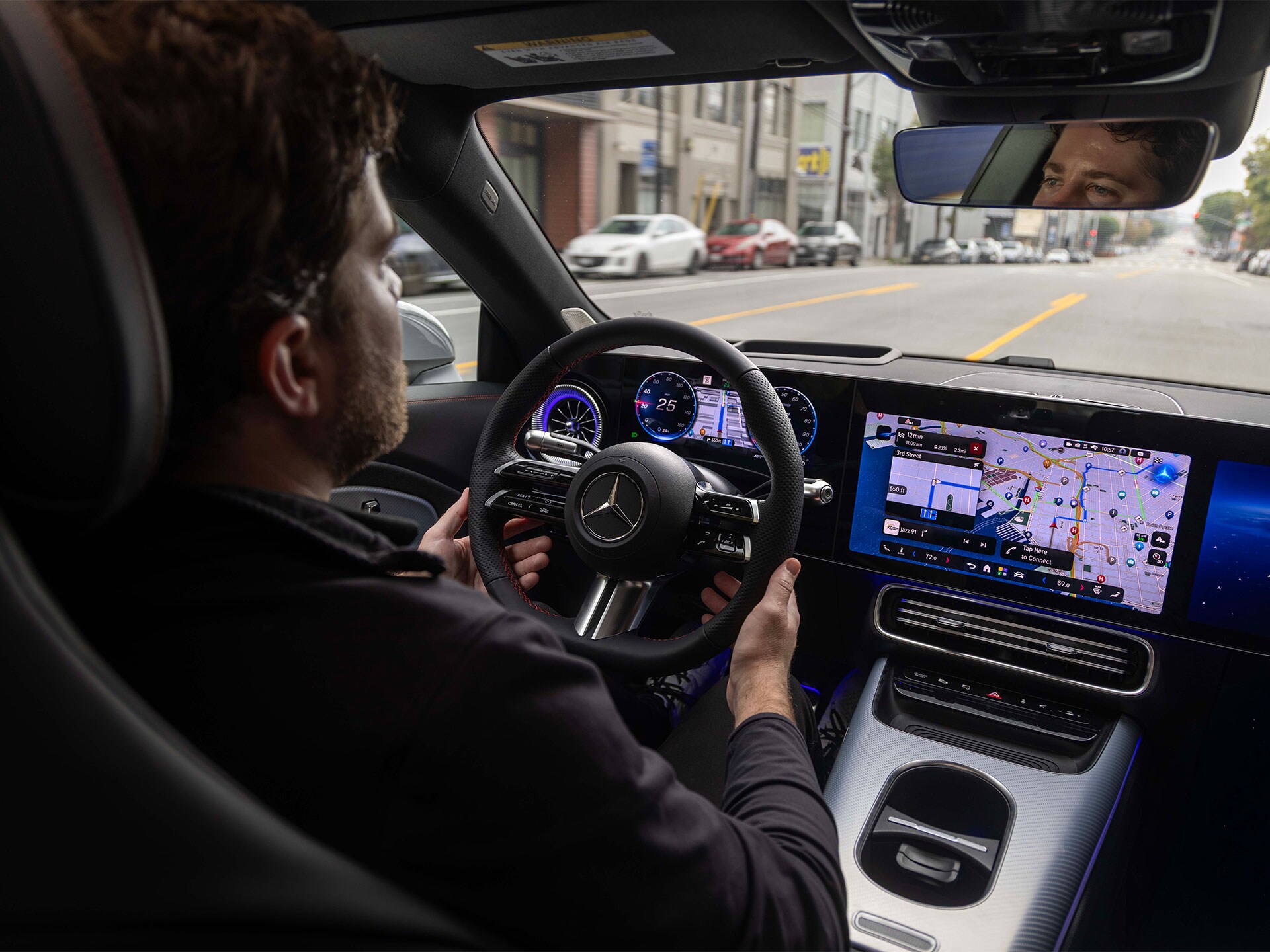 Ein mann sitzt im Cockpit eines Mercedes-Benz und fährt auf einer Straße mit gelben Markierungen.
