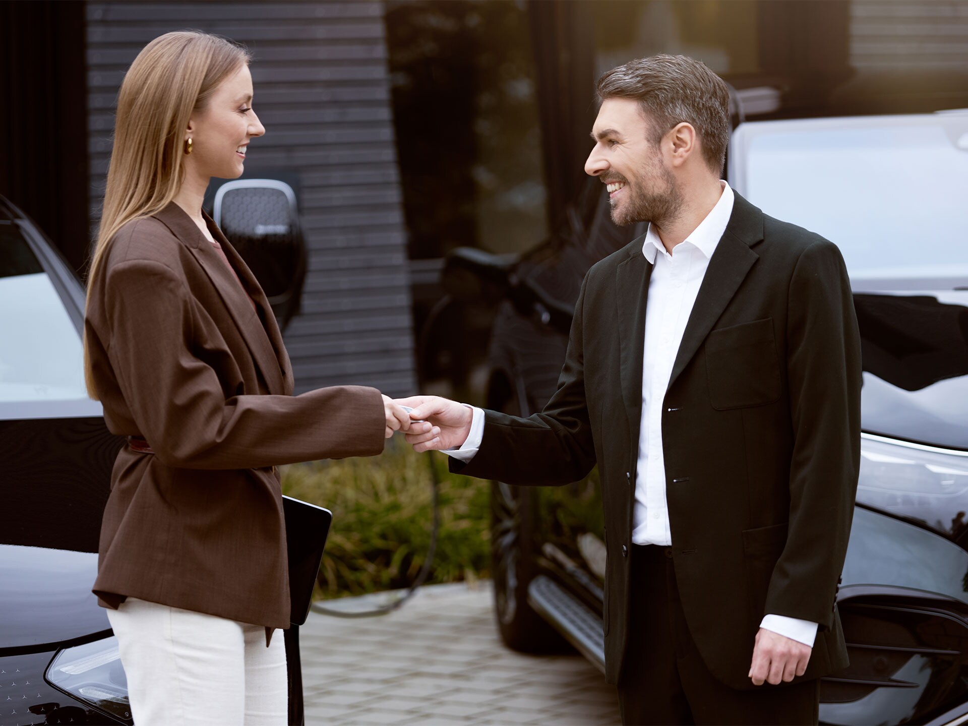 Zwei Personen schütteln sich die Hand, während im Hintergrund Mercedes-Benz Fahrzeuge laden.