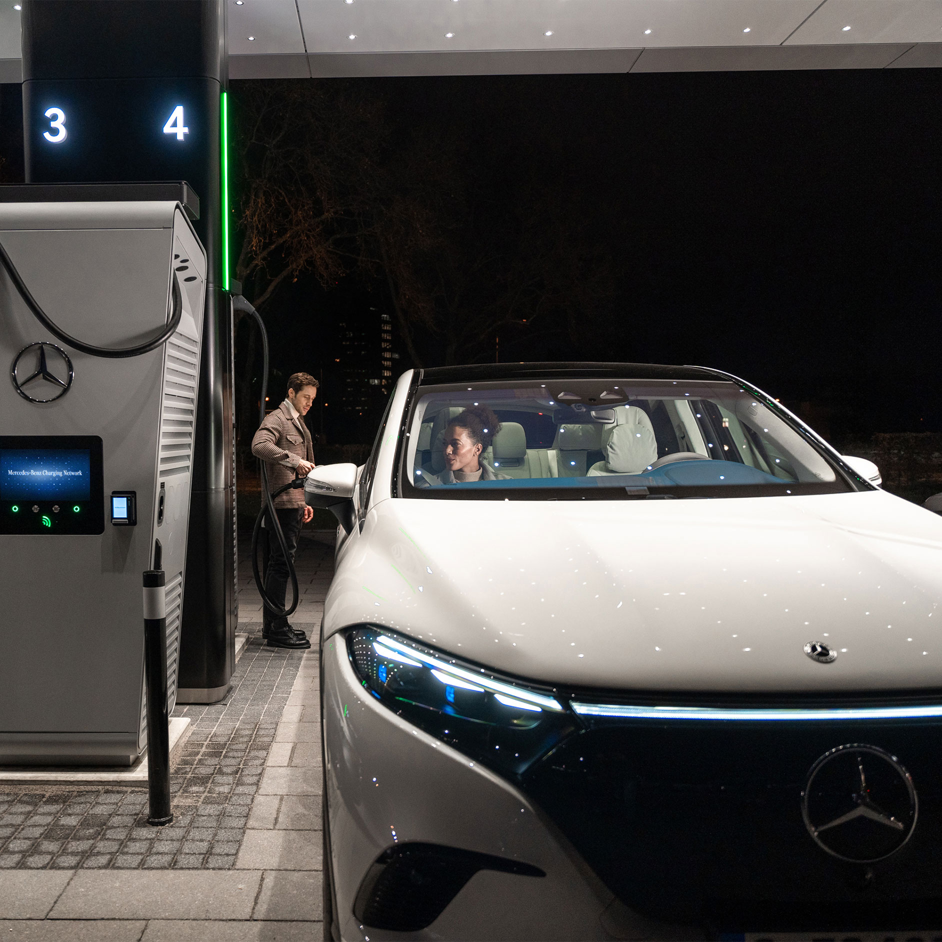 Öffentliches Laden | Laden | Mercedes-Benz Eine Person lädt einen Mercedes-Benz EQS SUV an einer Ladestation