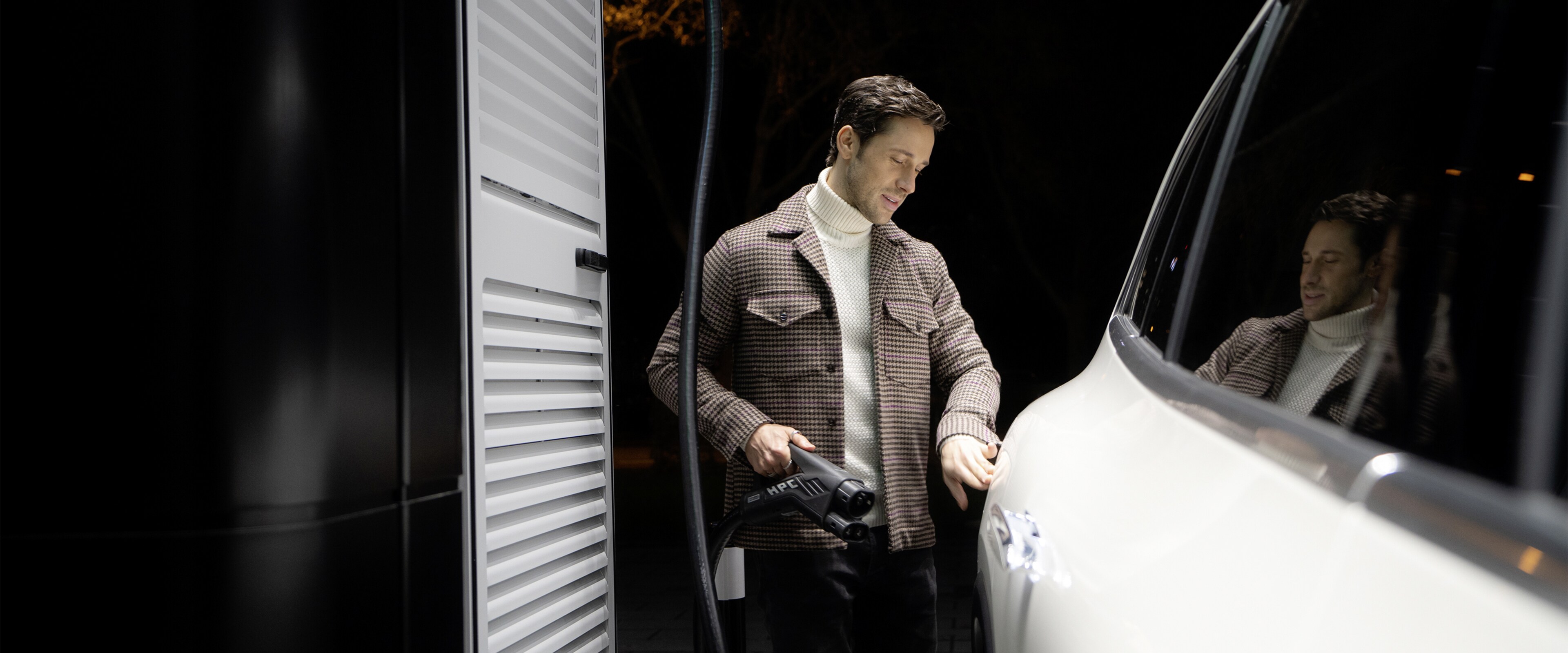 Ein Mann lädt seinen weißen Mercedes-Benz an einer Ladestation.