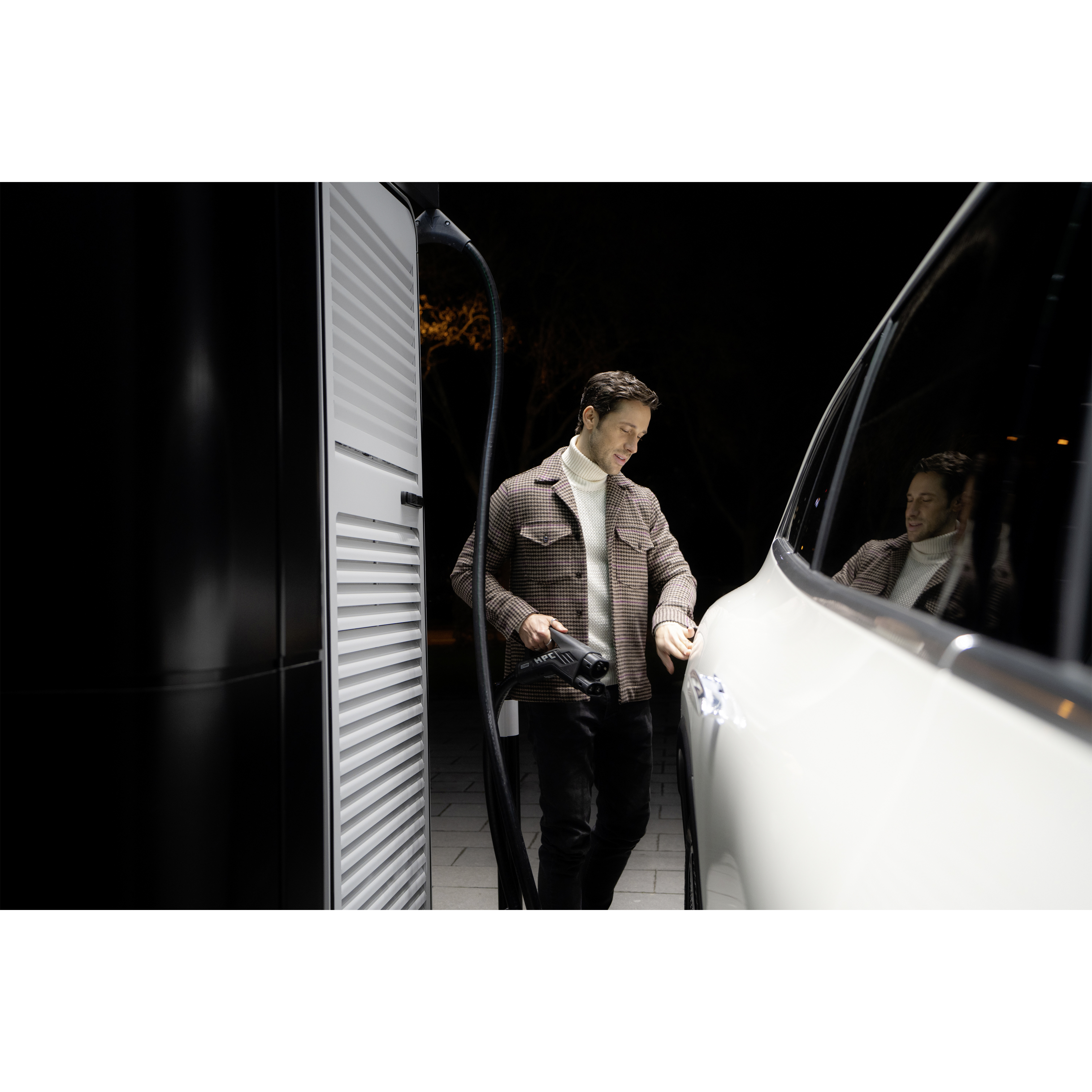 Laden | Ladelösungen | Mercedes-Benz. Ein Mann lädt seinen weißen Mercedes-Benz an einer Ladestation für Elektroautos.