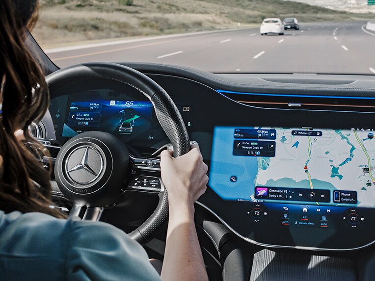 Eine Person fährt auf der Autobahn und lässt sich vom MBUX Navigationssystem von Mercedes-Benz zu einem Parkplatz navigieren.