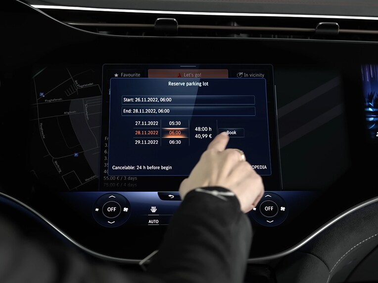 Eine Person tippt auf das Fahrzeugdisplay und bucht mit Off-Street Booking einen Parkplatz über das MBUX System.