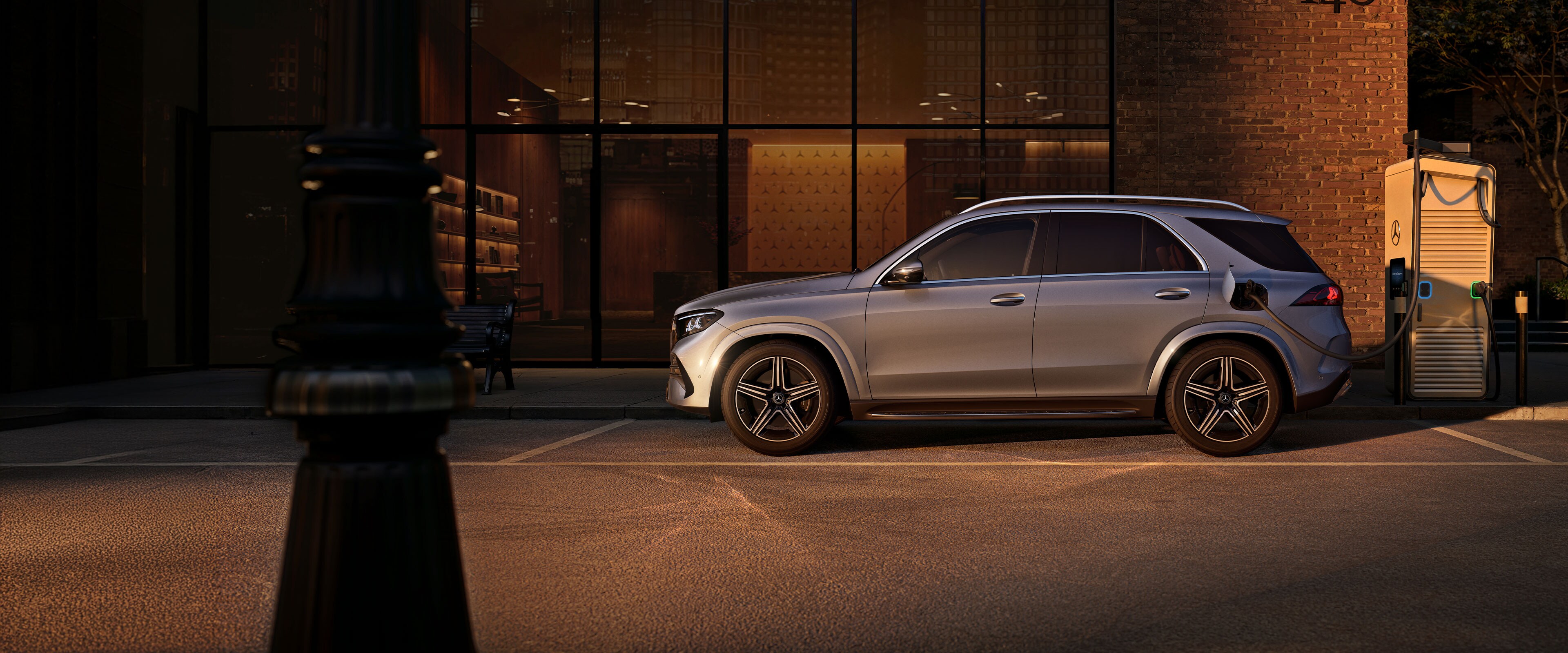 Ein silbergrauer Mercedes-Benz GLE SUV in einer Seitenansicht vor einem großen Haus.