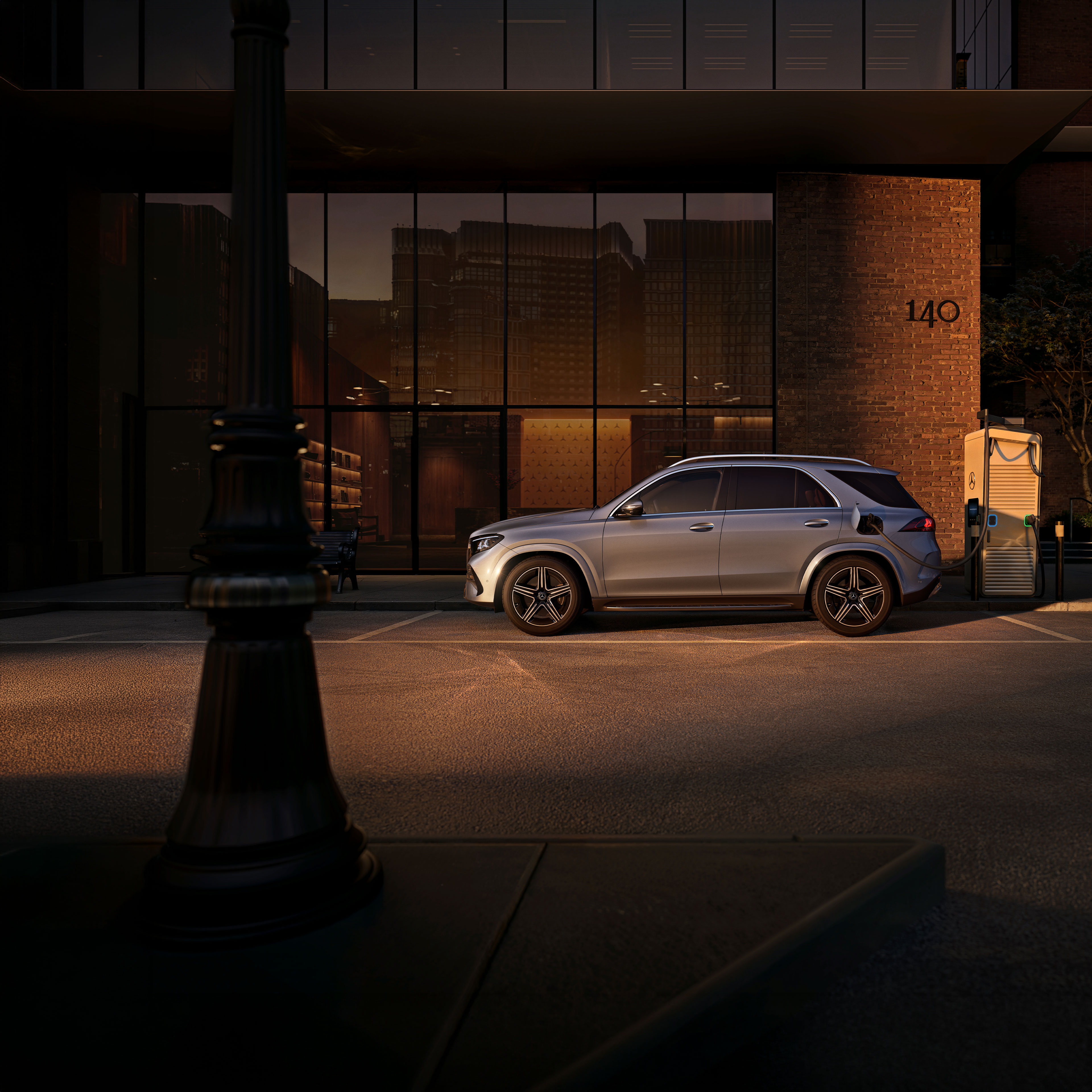 Modelle | Plug-in-Hybride | Mercedes-Benz. Ein silbergrauer Mercedes-Benz GLE SUV in einer Seitenansicht vor einem großen Haus.