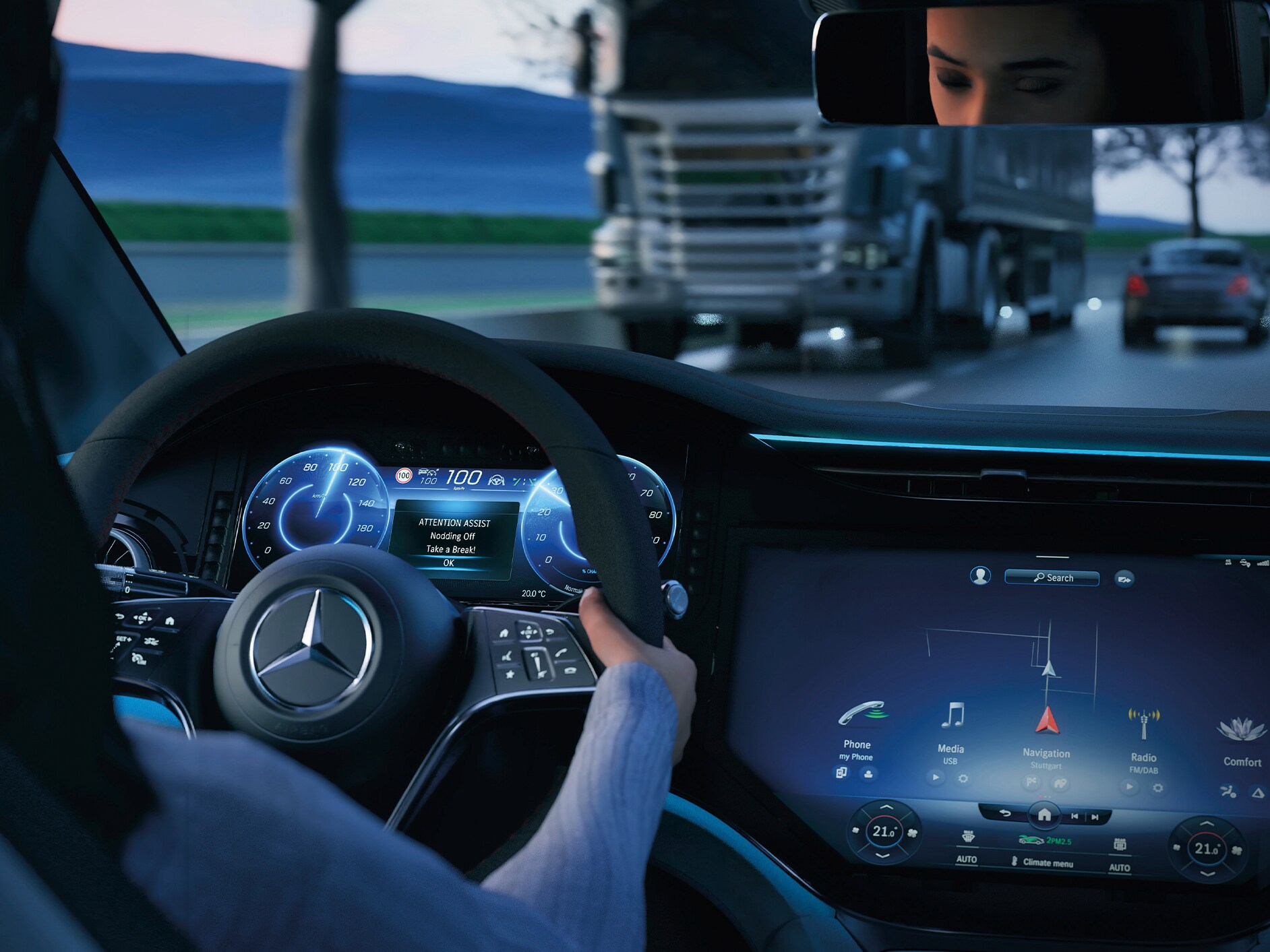 Innenansicht des Cockpits eines Mercedes-Benz Fahrzeugs mit einer Fahrerin am Steuer.