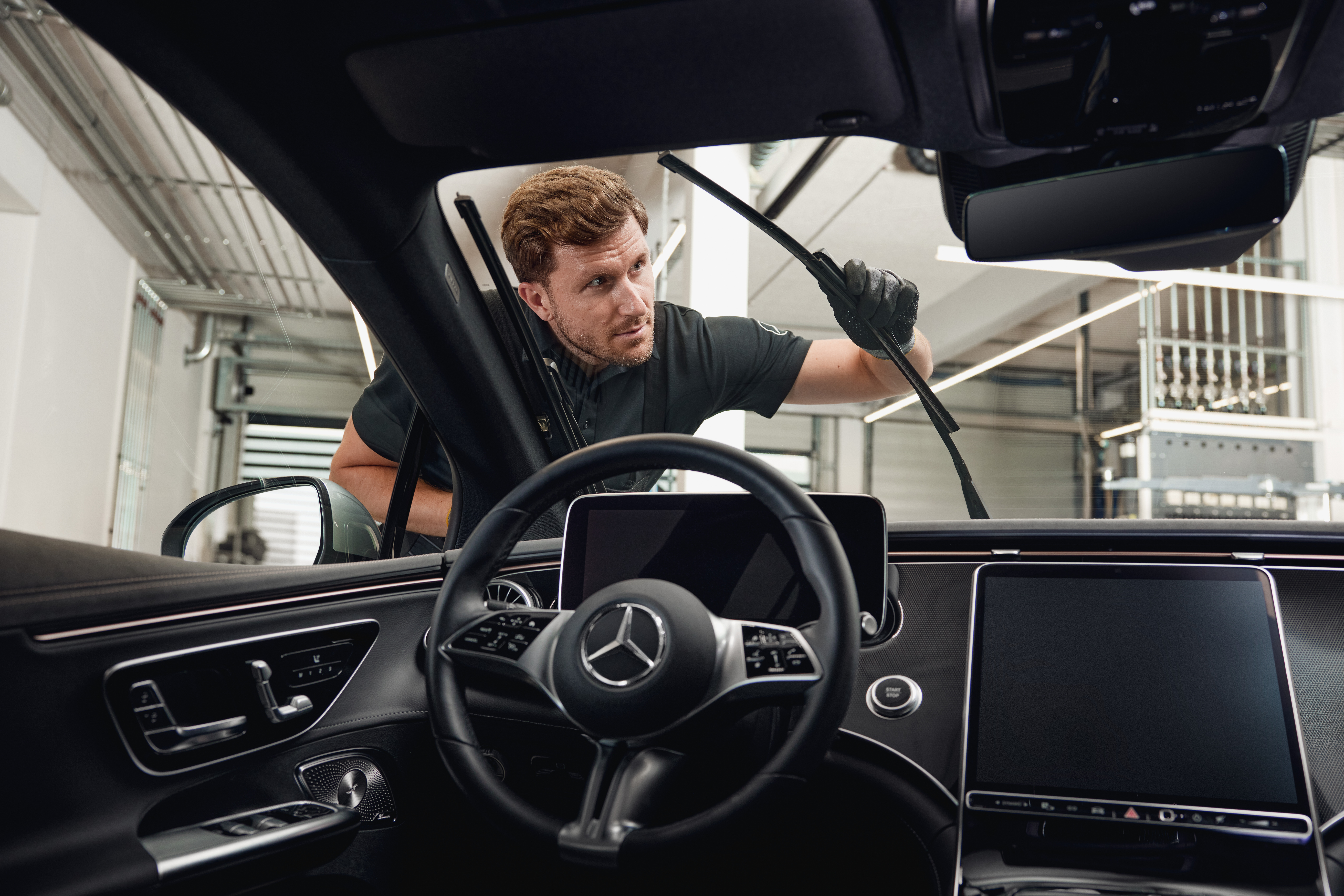 Ersatzteile | Mercedes-Benz Innenansicht eines Mercedes-Benz-Fahrzeugs, in dem ein Techniker Original-Scheibenwischerblätter austauscht.