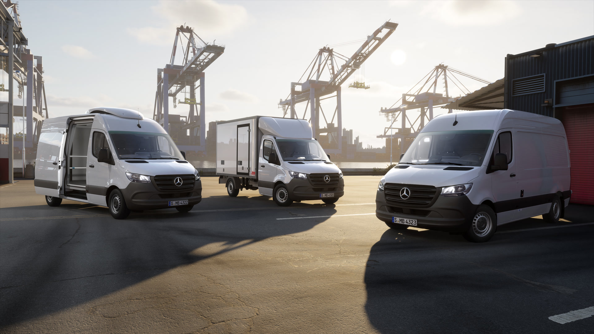 IAA | Mercedes-Benz Transporter. Drei verschiedene Aufbaumodelle auf einem Parkplatz an einem Hafen vor Gegenlicht.