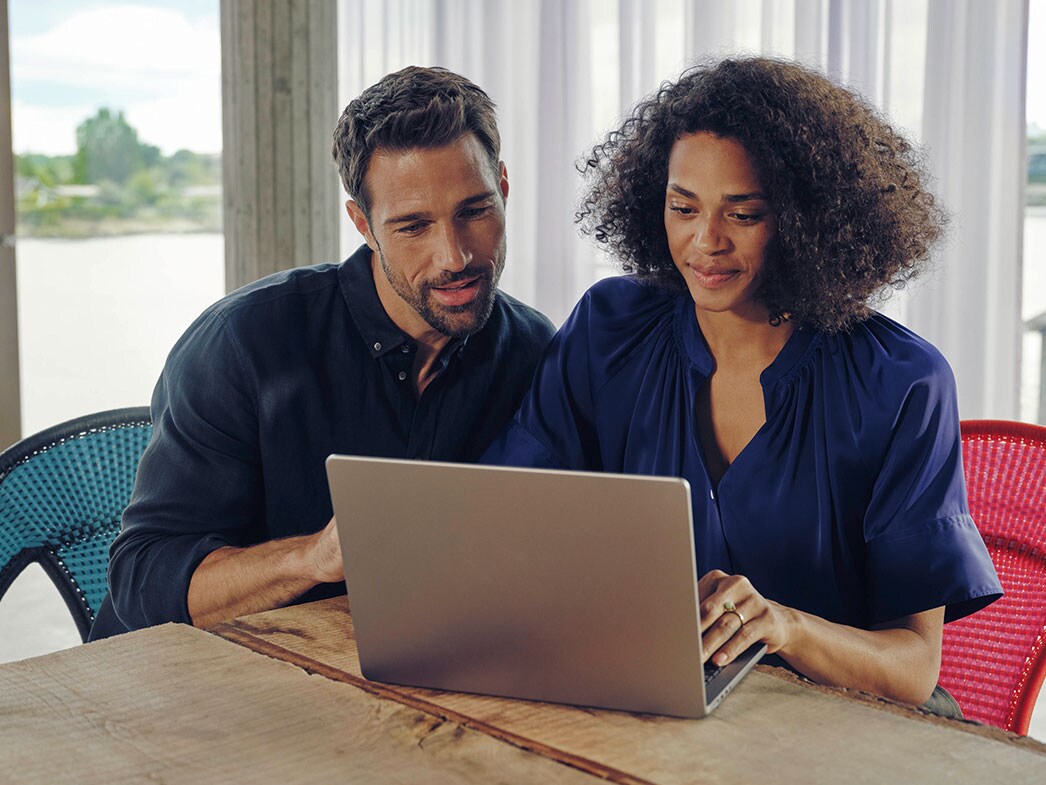 Mann und Frau sitzen am Tisch und schauen gemeinsam auf einen Laptop