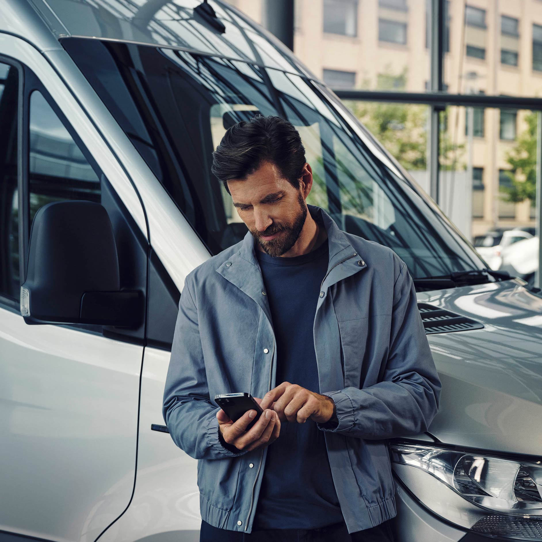 Abo | Financial Services | Mercedes-Benz Transporter Mann steht neben einem weißen Mercedes-Benz eSprinter Van und telefoniert