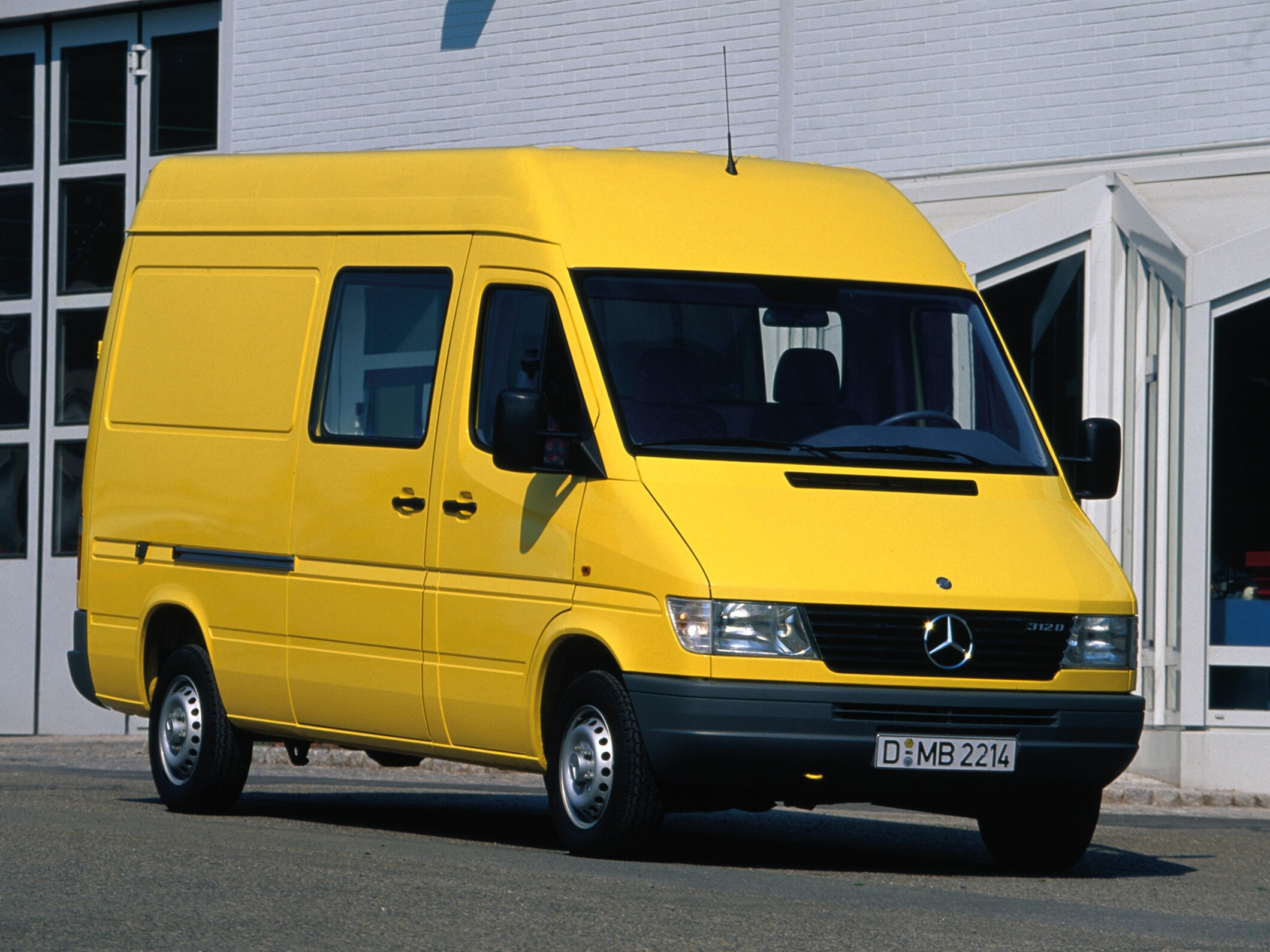 Ein Sprinter der ersten Generation, der vor einer Industriehalle geparkt ist.