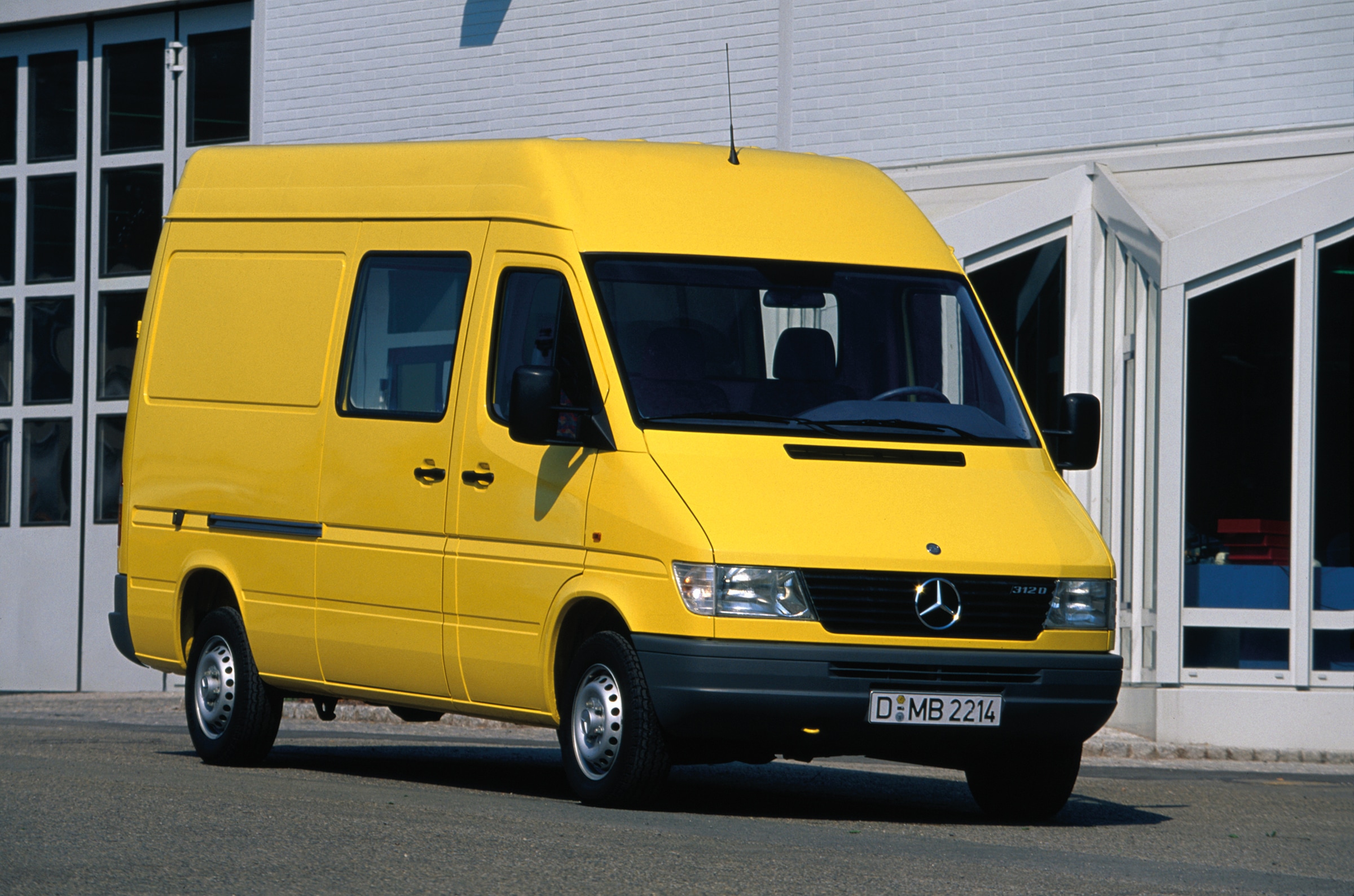 Geschichte | Mercedes-Benz Transporter. Ein Sprinter der ersten Generation, der vor einer Industriehalle geparkt ist.