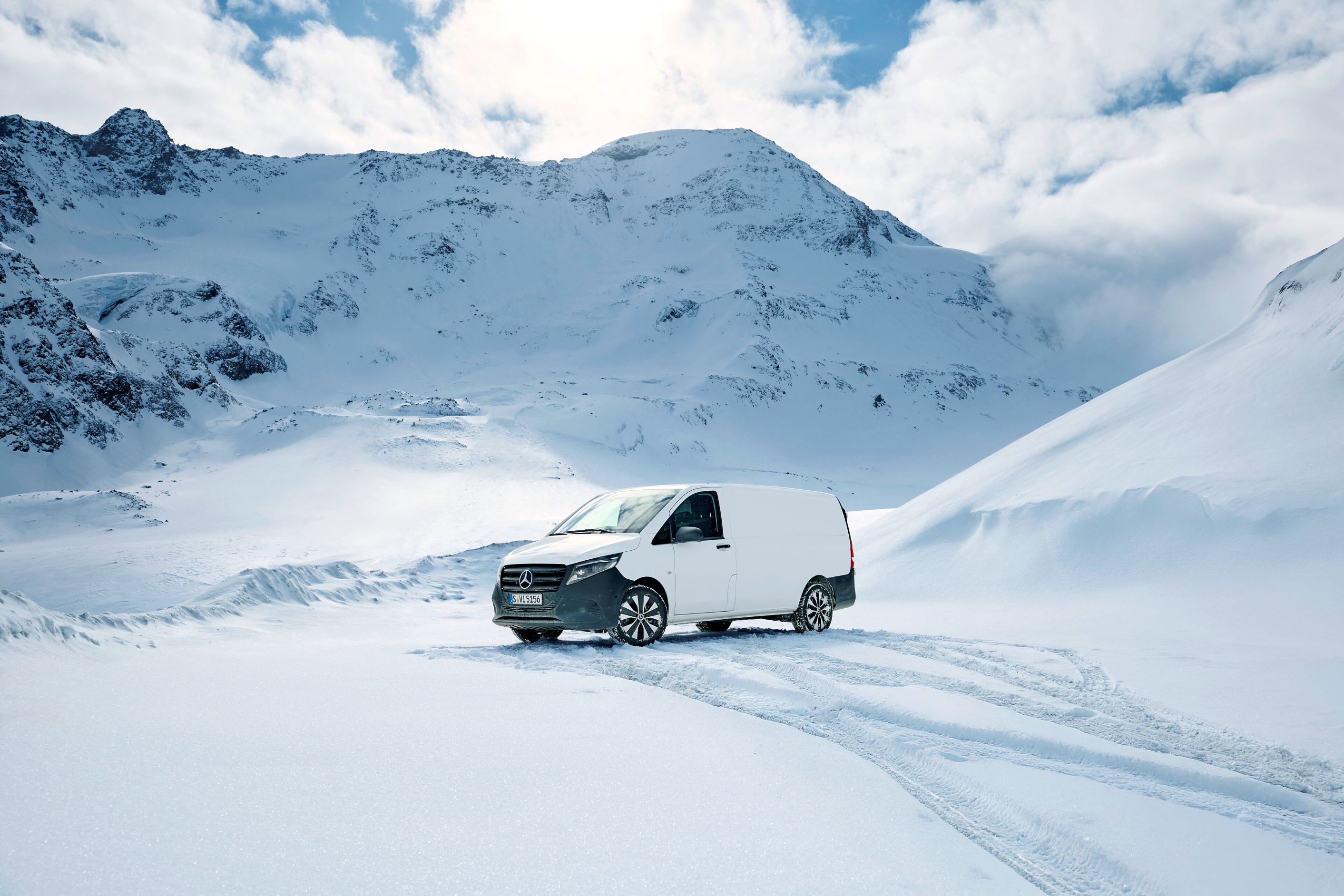 4x4-Plakette | 4x4 | Mercedes-Benz Ein weißer Transporter steht auf dem Schnee zwischen beschneiten Bergen.