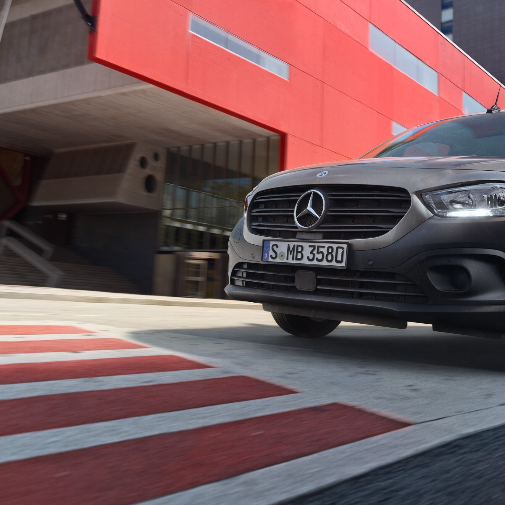 Der Citan Tourer, ein kompakter Personentransporter von Mercedes-Benz, fährt durch ein modernes Stadtgebiet.