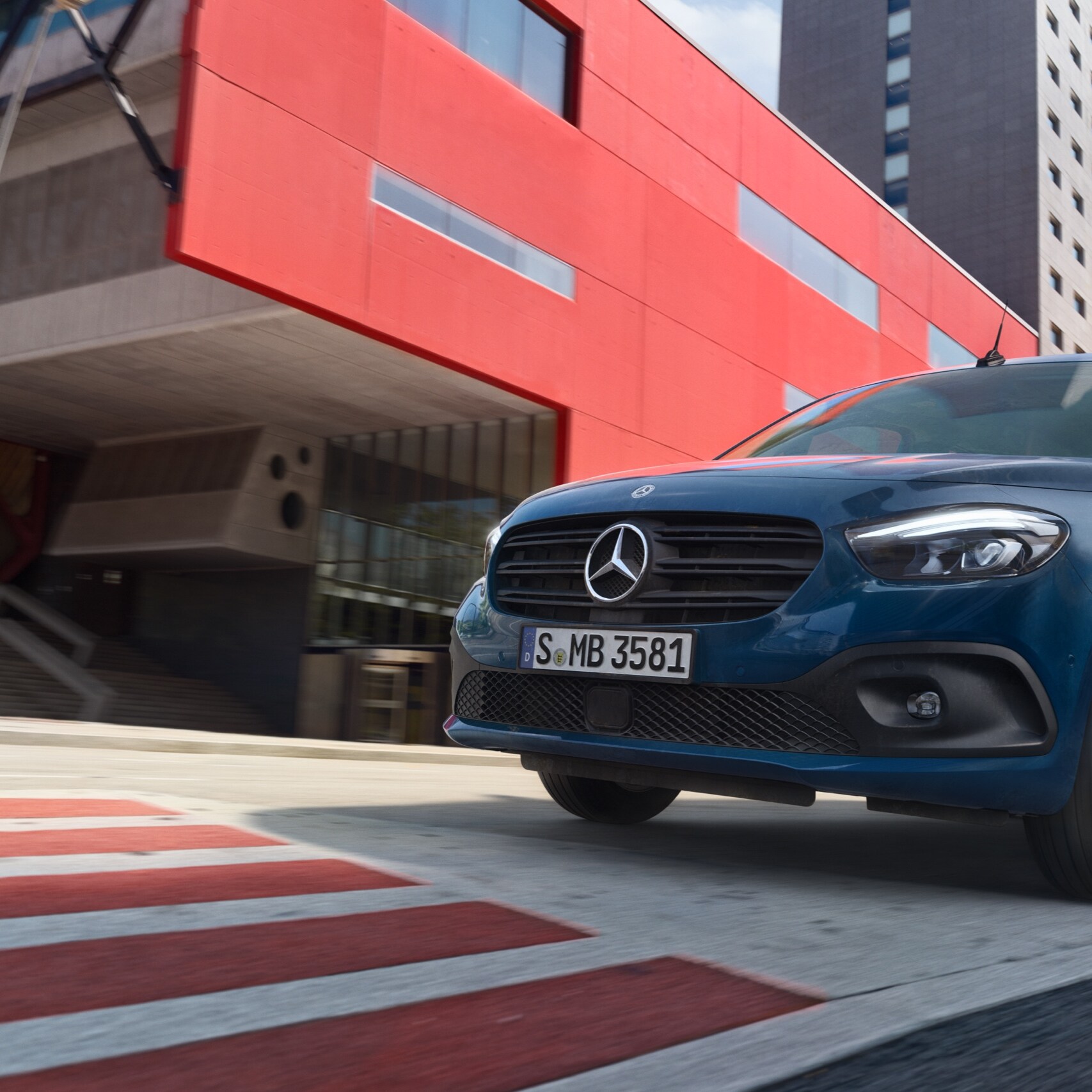 Der eCitan Tourer, ein elektrischer Personentransporter von Mercedes-Benz, fährt durch ein modernes Stadtgebiet.