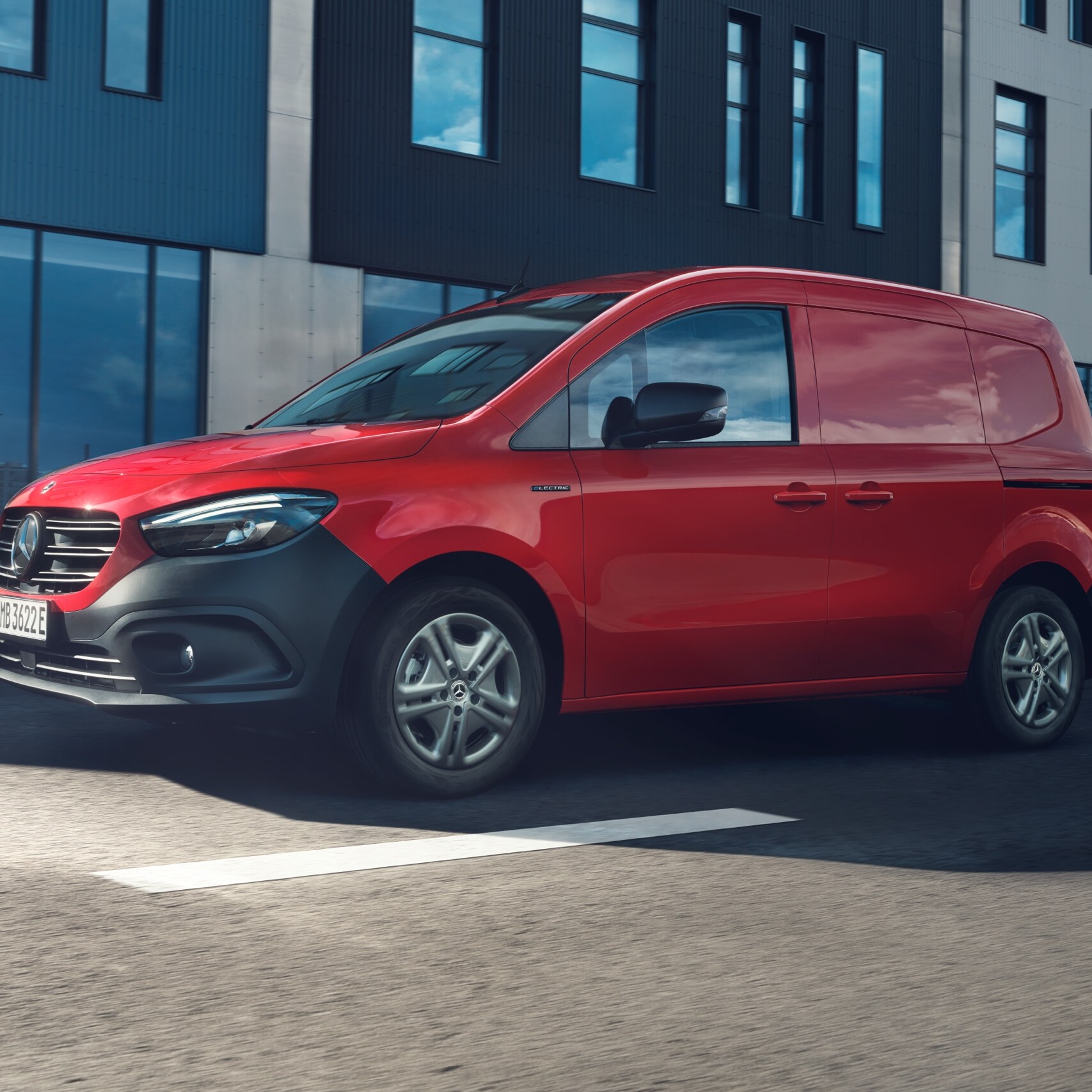Ein roter Mercedes-Benz eCitan Kastenwagens fährt durch eine Stadt bei Sonnenschein.
