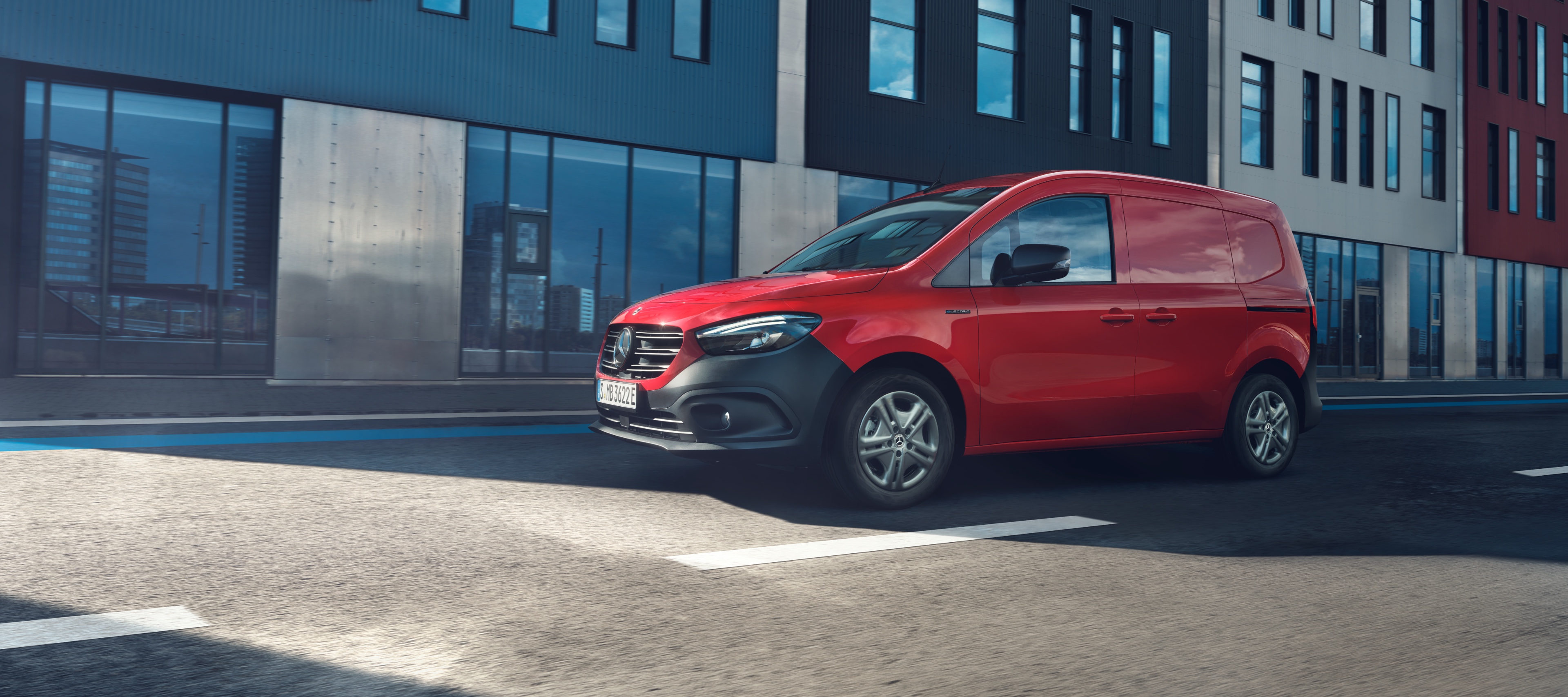 Alternative Antriebe | Citan Kastenwagen | Mercedes-Benz Ein roter Mercedes-Benz eCitan Kastenwagens fährt durch eine Stadt bei Sonnenschein.
