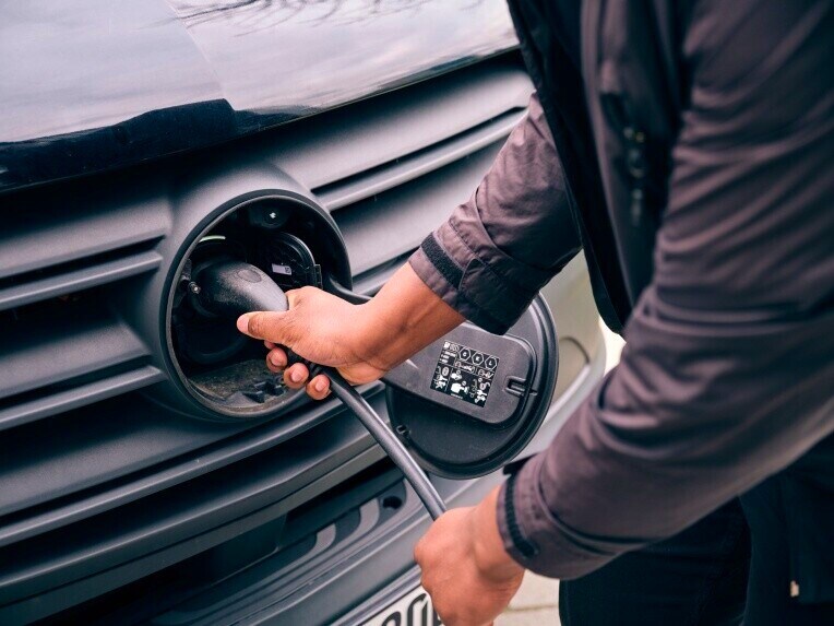 Eine Person bedient das Ladekabel an der CCS-Ladedose des Mercedes-Benz eSprinter Fahrgestells.