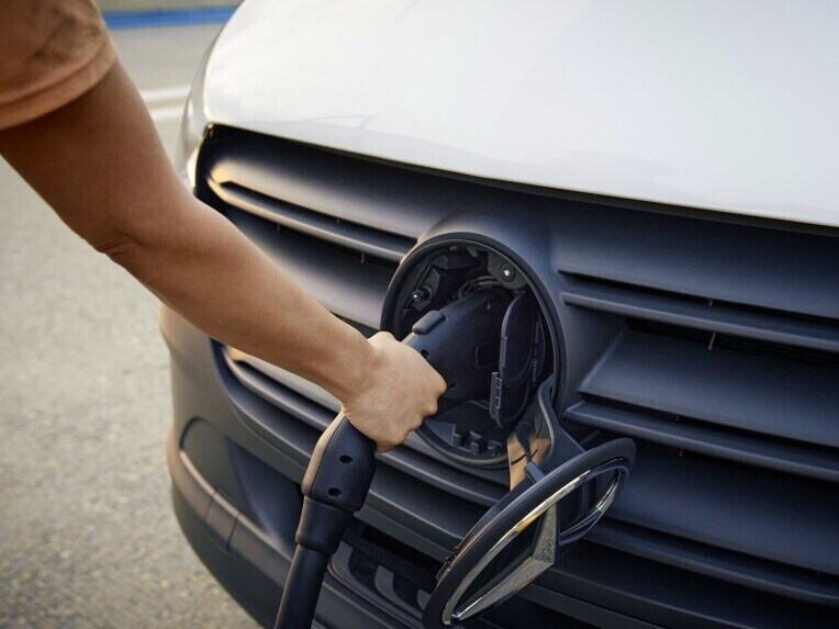 Eine Person bedient das Ladekabel an der CCS-Ladedose des Mercedes-Benz eSprinter Fahrgestells.