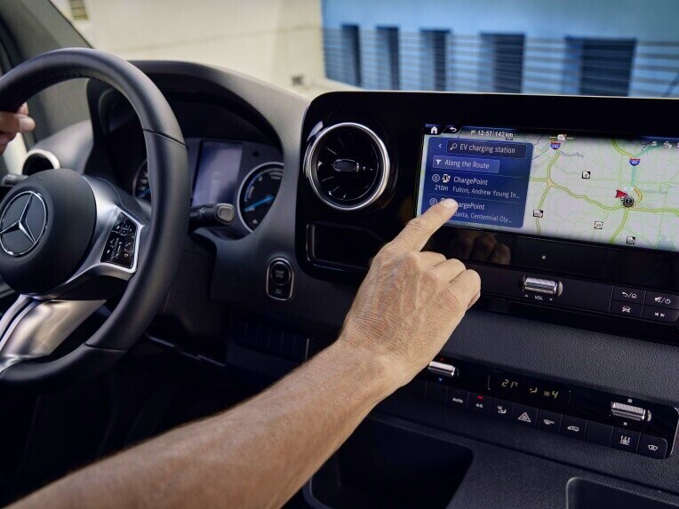 Eine Person bedient eine Navigation über das MBUX Multimediasystem im Mercedes-Benz eSprinter Fahrgestell.