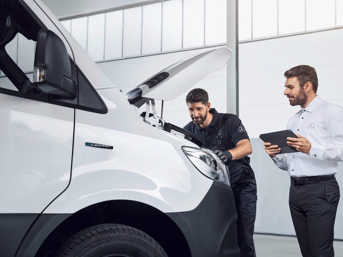 Zwei Mercedes-Benz Mitarbeiter schauen in den Motor eines weißen Vitos.