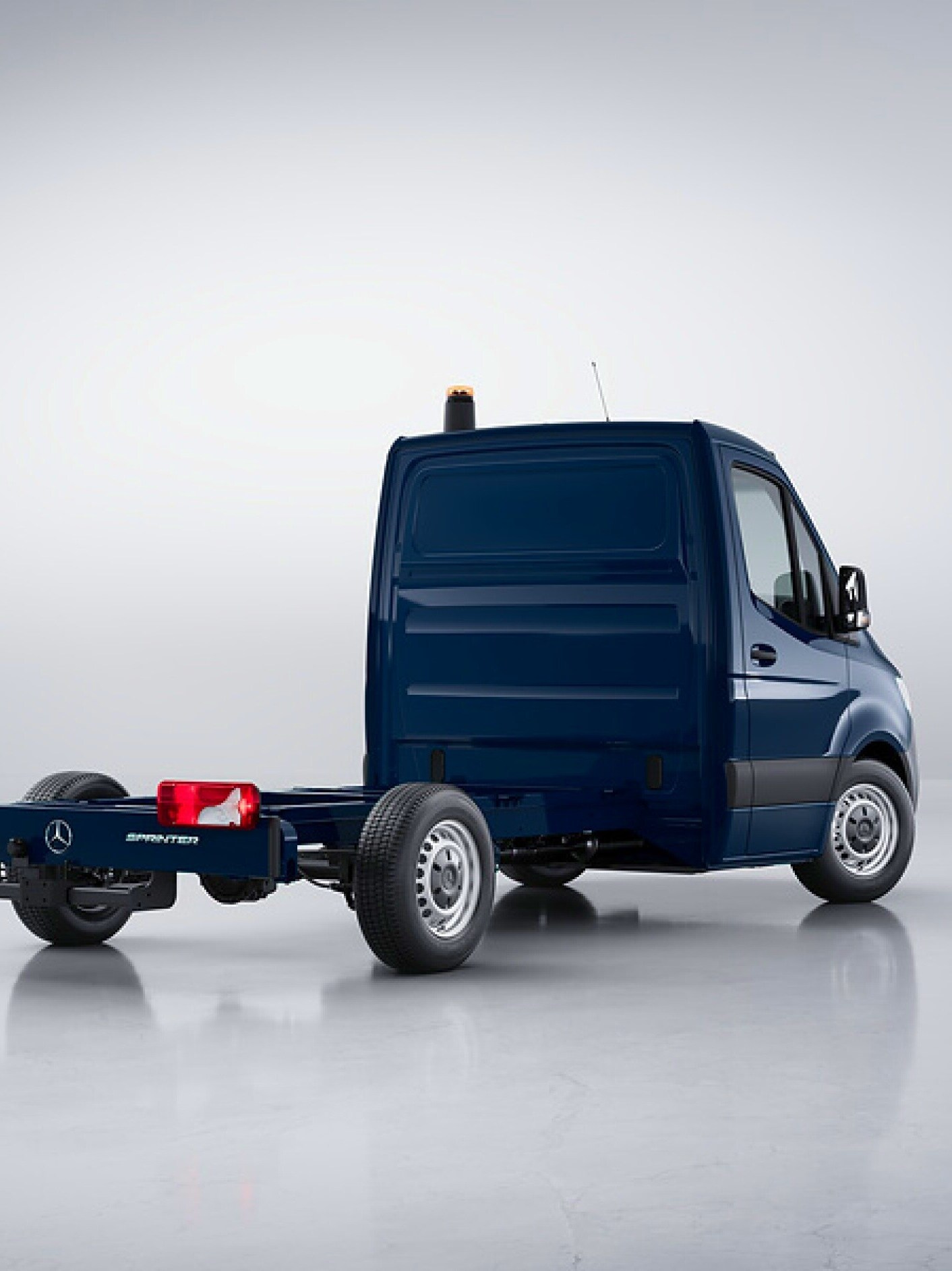 Eine seitliche Heckansicht des dunkelblauen Mercedes-Benz Sprinter Fahrgestell in einer hellen Studioumgebung.