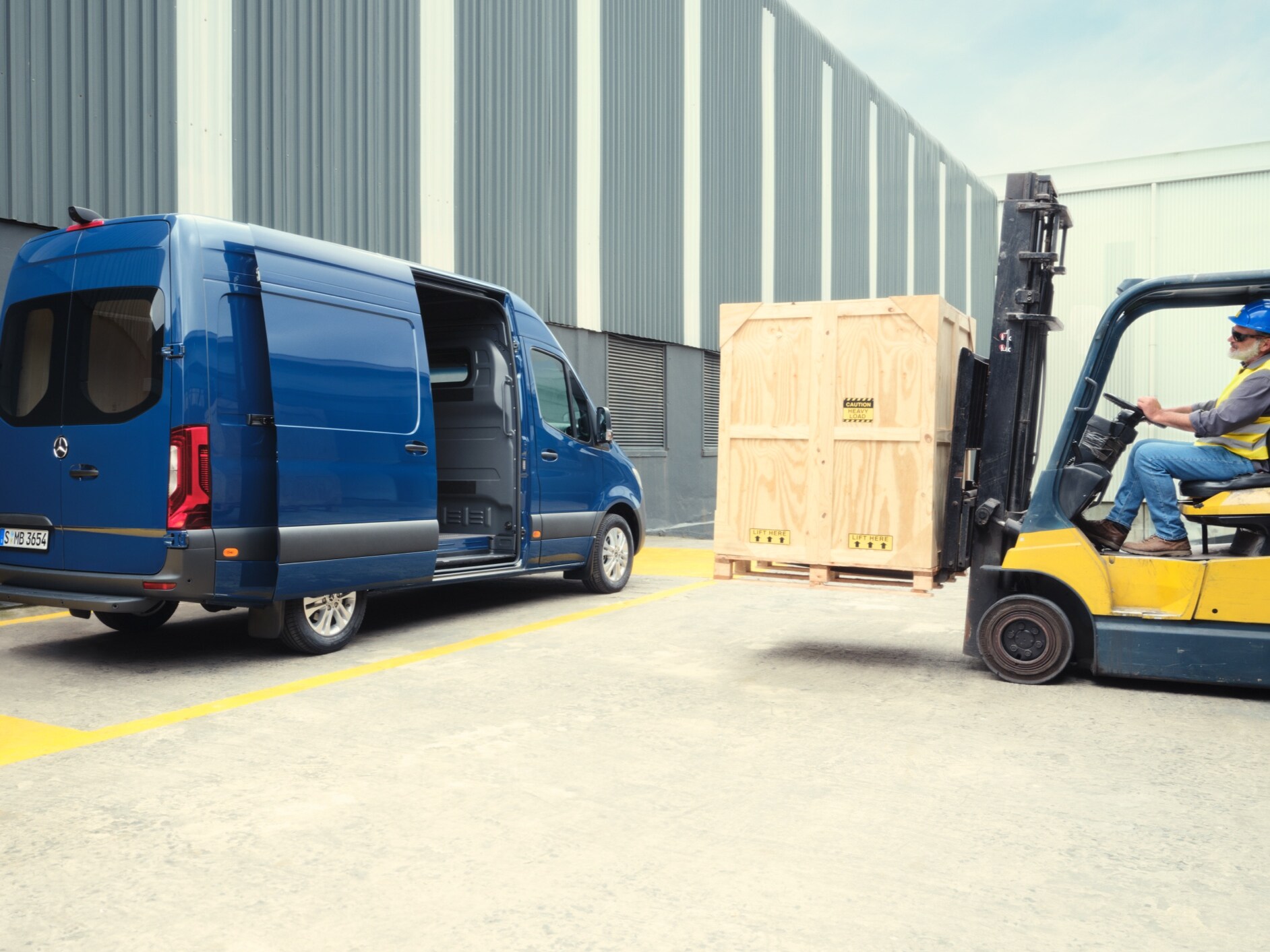 Ein blauer Mercedes-Benz Sprinter Kastenwagen wird von einem Gabelstapler beladen.