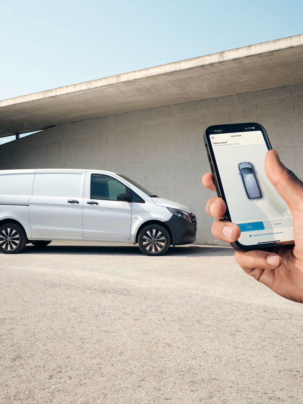 Eine Hand hält ein Smartphone hoch, das die Mercedes me App zeigt. Vito Kastenwagen im Hintergrund.