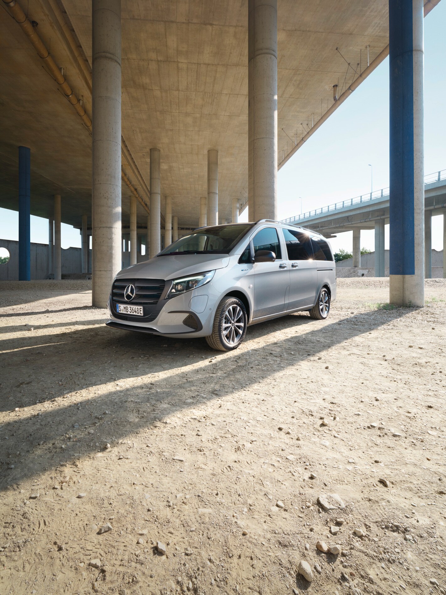 Eine seitliche Frontansicht des silbernen eVito Tourer, der unter einer Brücke steht.