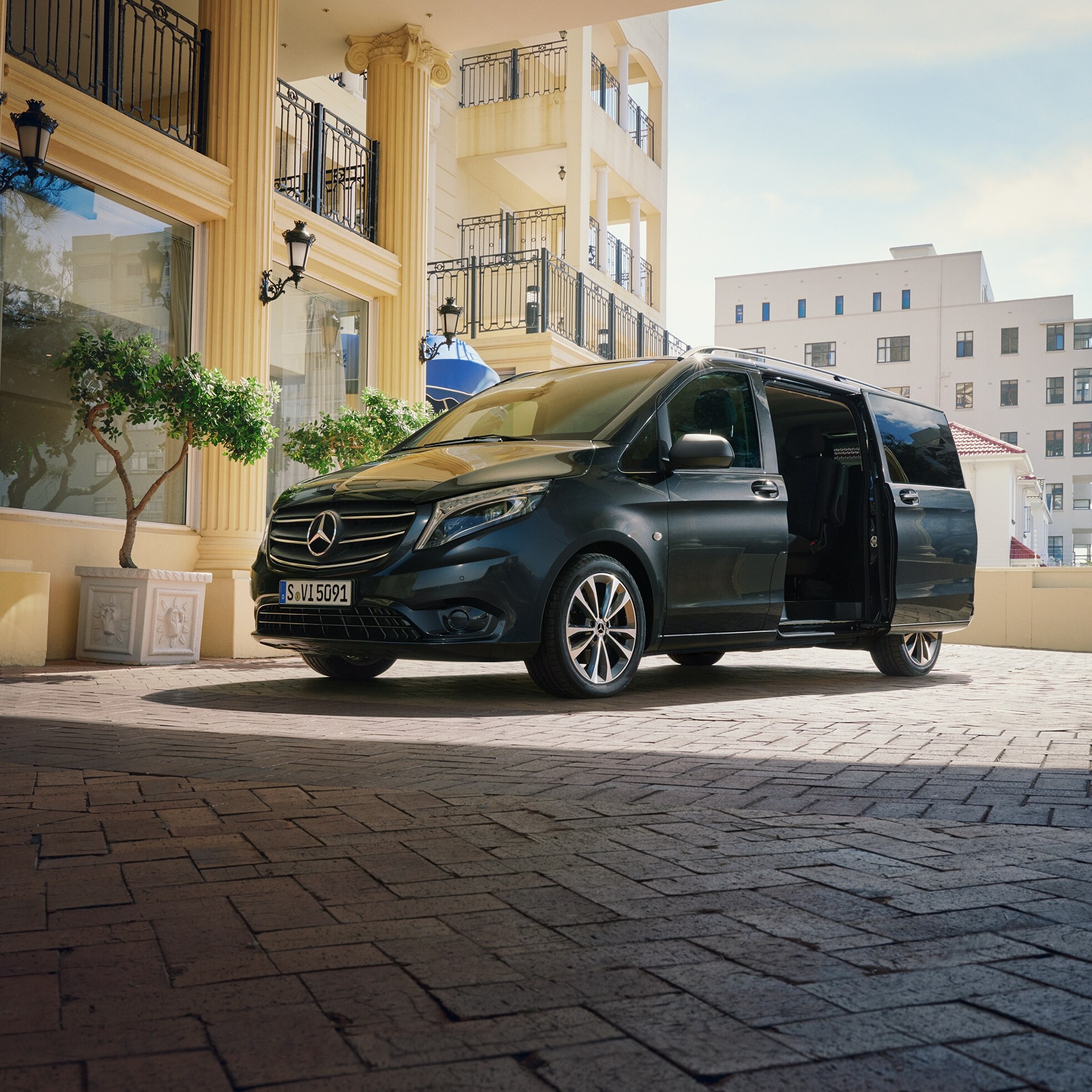 Ein Mercedes‑Benz Vito Tourer, der vor dem Eingang eines repräsentativen Gebäudes geparkt ist.