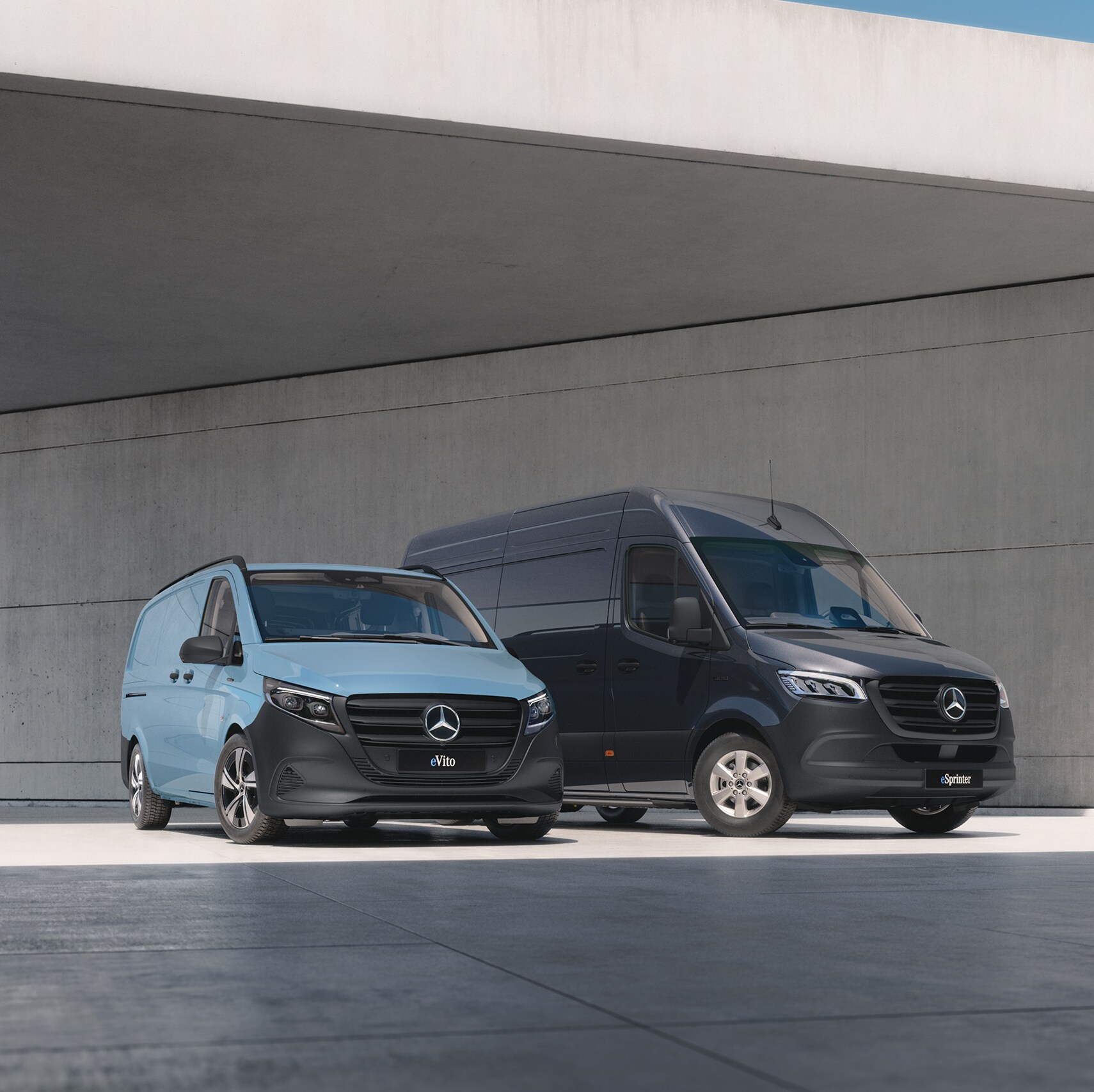 Drei Transporter-Modelle von Mercedes-Benz stehen an einer Betonbrücke im Sonnenschein.