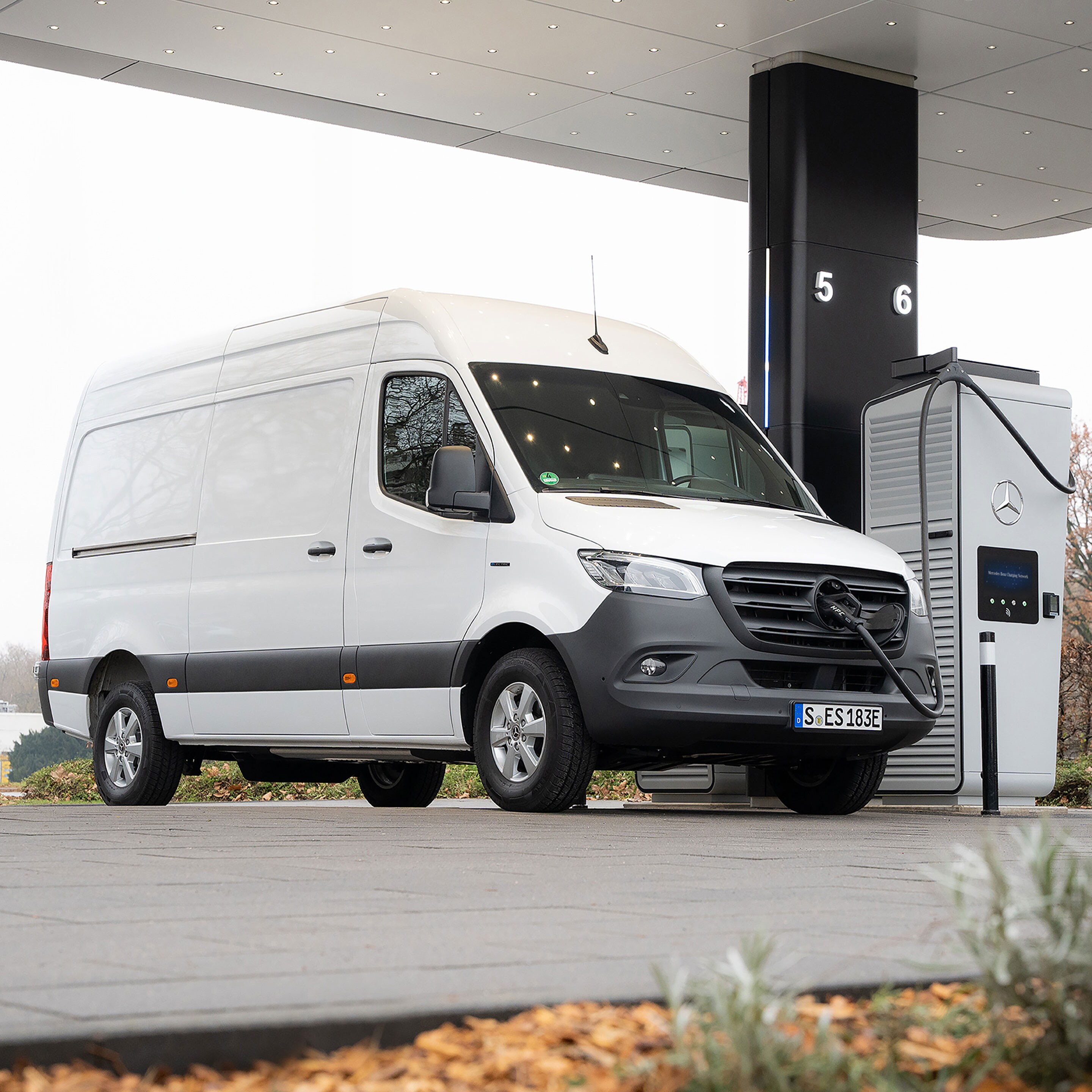 Ein weißer Sprinter Kastenwagen, wird an einer E-Ladesäule geladen.