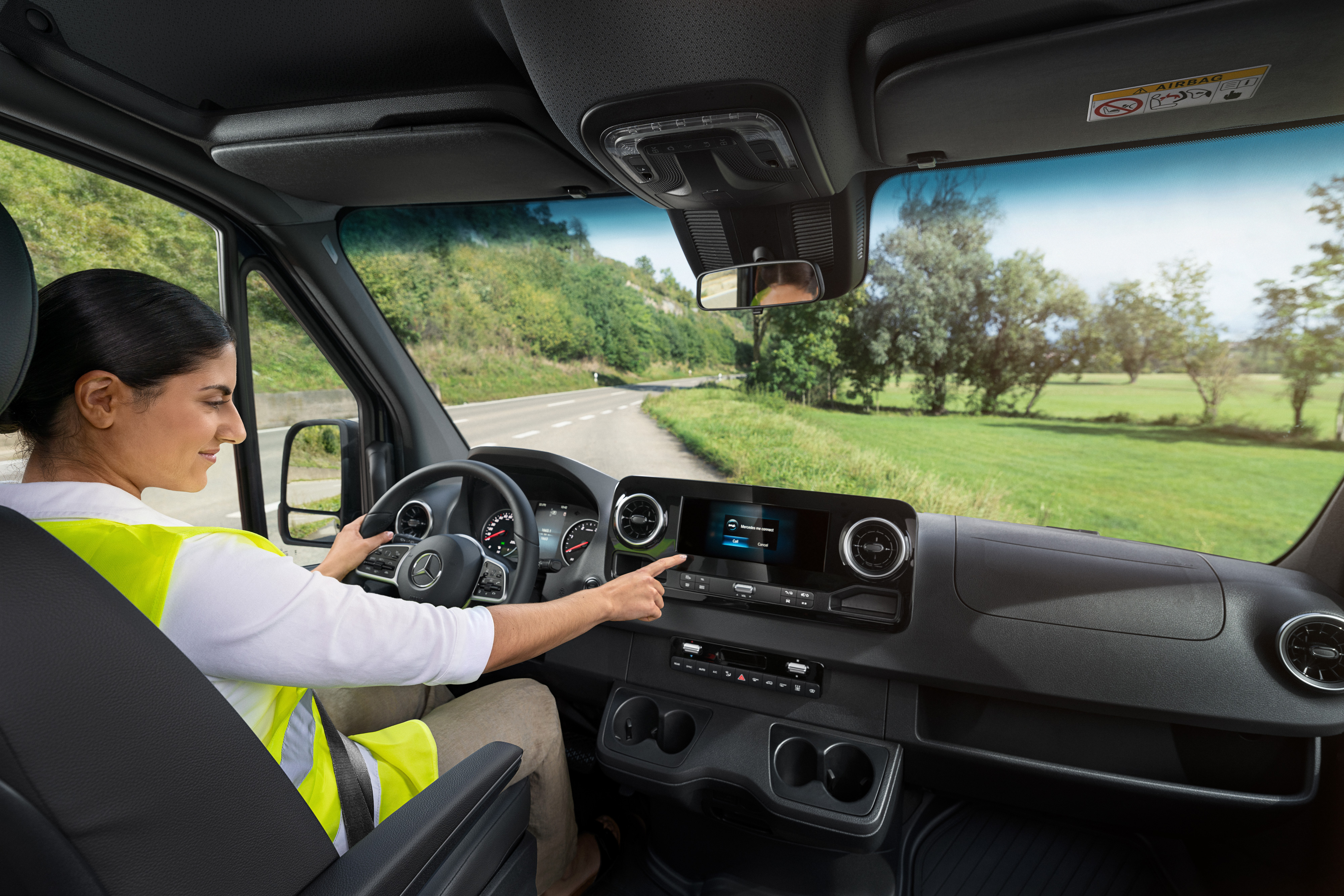 MobiloVan | Mercedes-Benz Transporter. Fahrerin im Mercedes-Van prüft Borddisplay – unterstützt durch Mobilitätsgarantie-Versicherung für unterwegs.