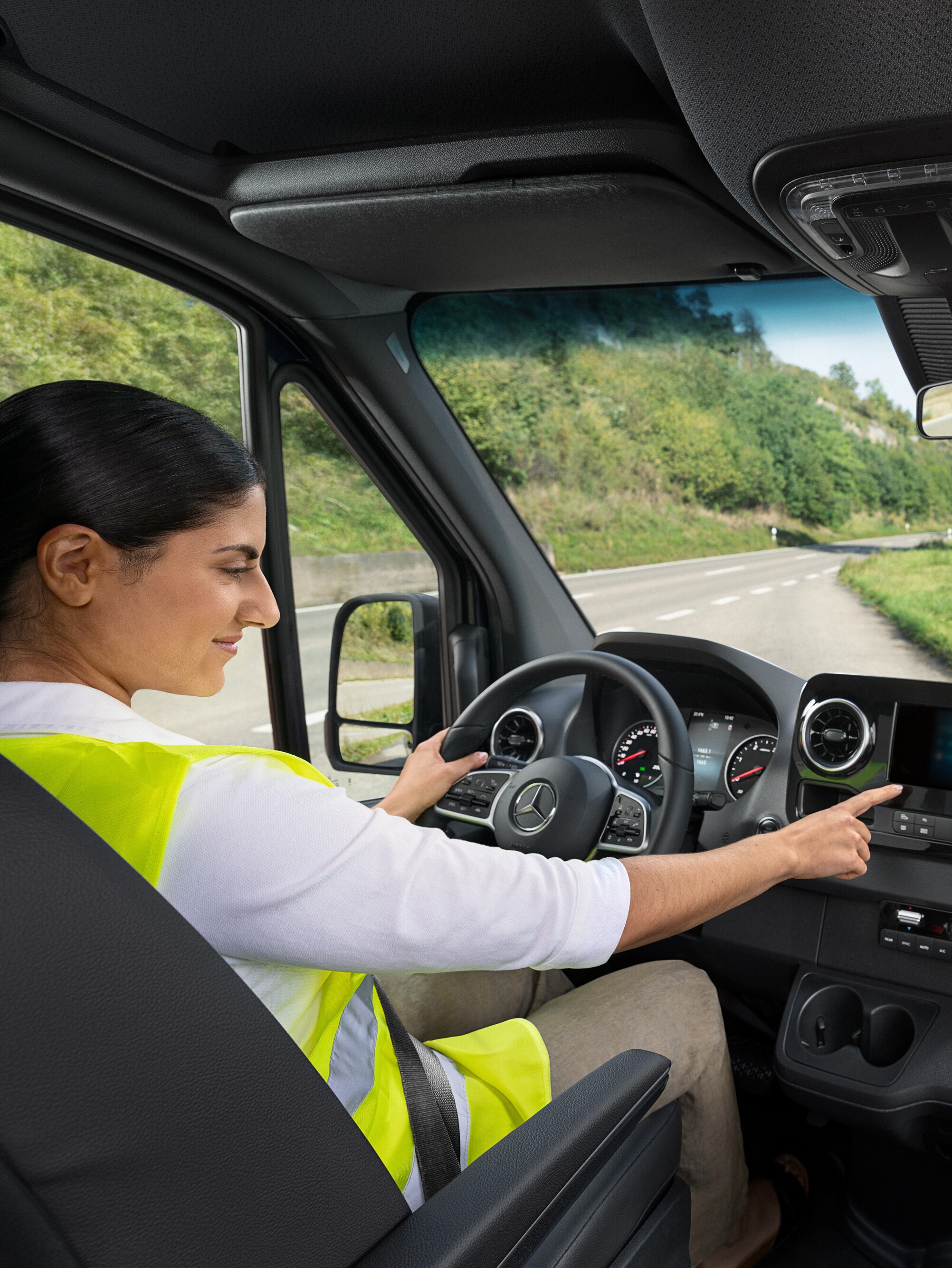 Fahrerin im Mercedes-Van prüft Borddisplay – unterstützt durch Mobilitätsgarantie-Versicherung für unterwegs.