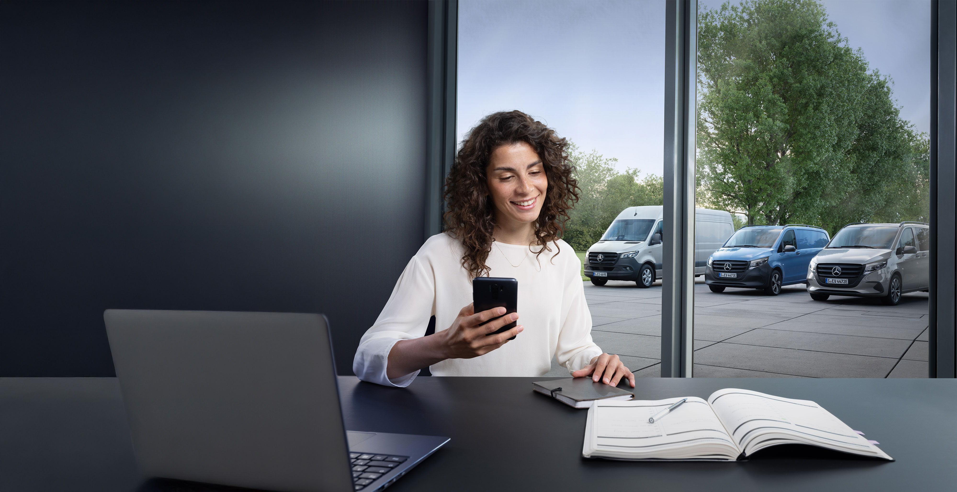 Mobilitätslösungen | Mercedes-Benz Transporter. Frau organisiert über Smartphone einen Mercedes-Benz Abhol- und Bringservice für individuelle Mobilität und Fahrzeugannahme.