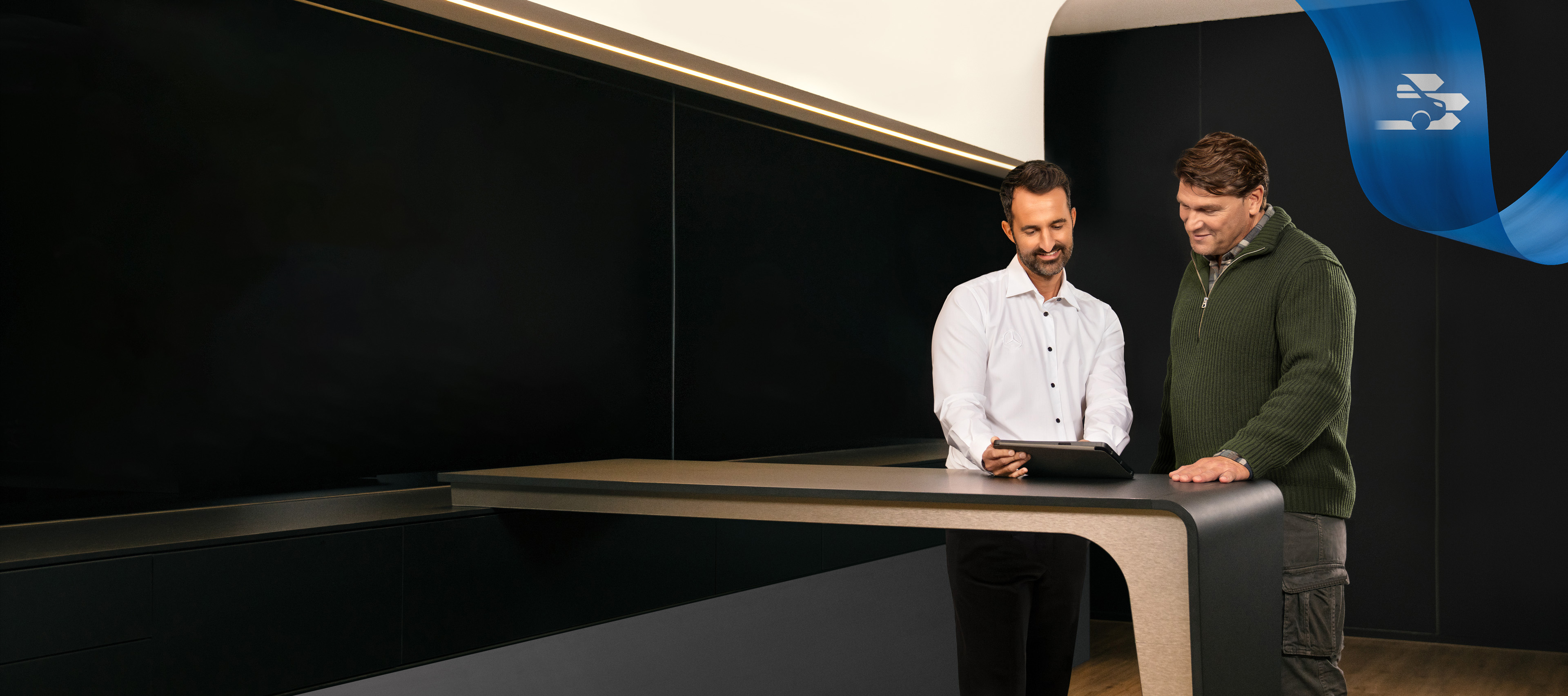 Servicepartner | Mercedes-Benz Transporter. Zwei Männer stehen im Büro eines Mercedes-Benz Service-Partners und diskutieren über etwas, das sie auf einem Tablet gesehen haben