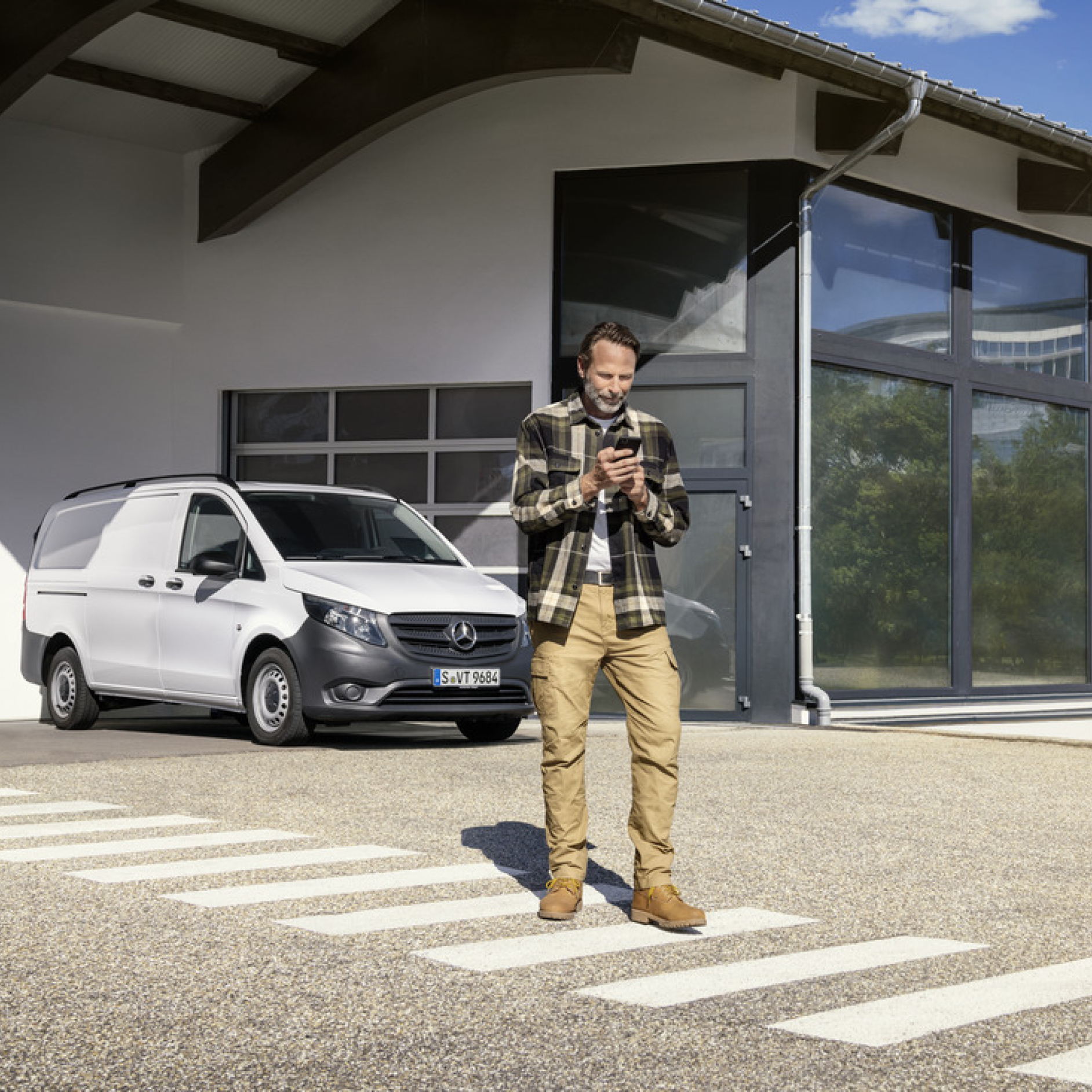 Mercedes-Benz Store | Digitale Extra | Mercedes-Benz Eine Person mit Smartphone vor einem Mercedes-Benz Vito.