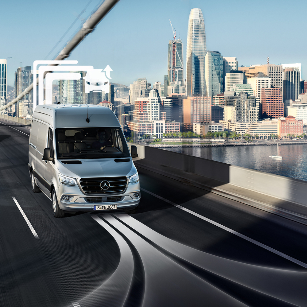 Van Uptime Monitor | Mercedes-Benz Transporter. Ein Mercedes-Benz Transporter fährt über eine Brücke in einer Großstadt mit Hochhäusern.