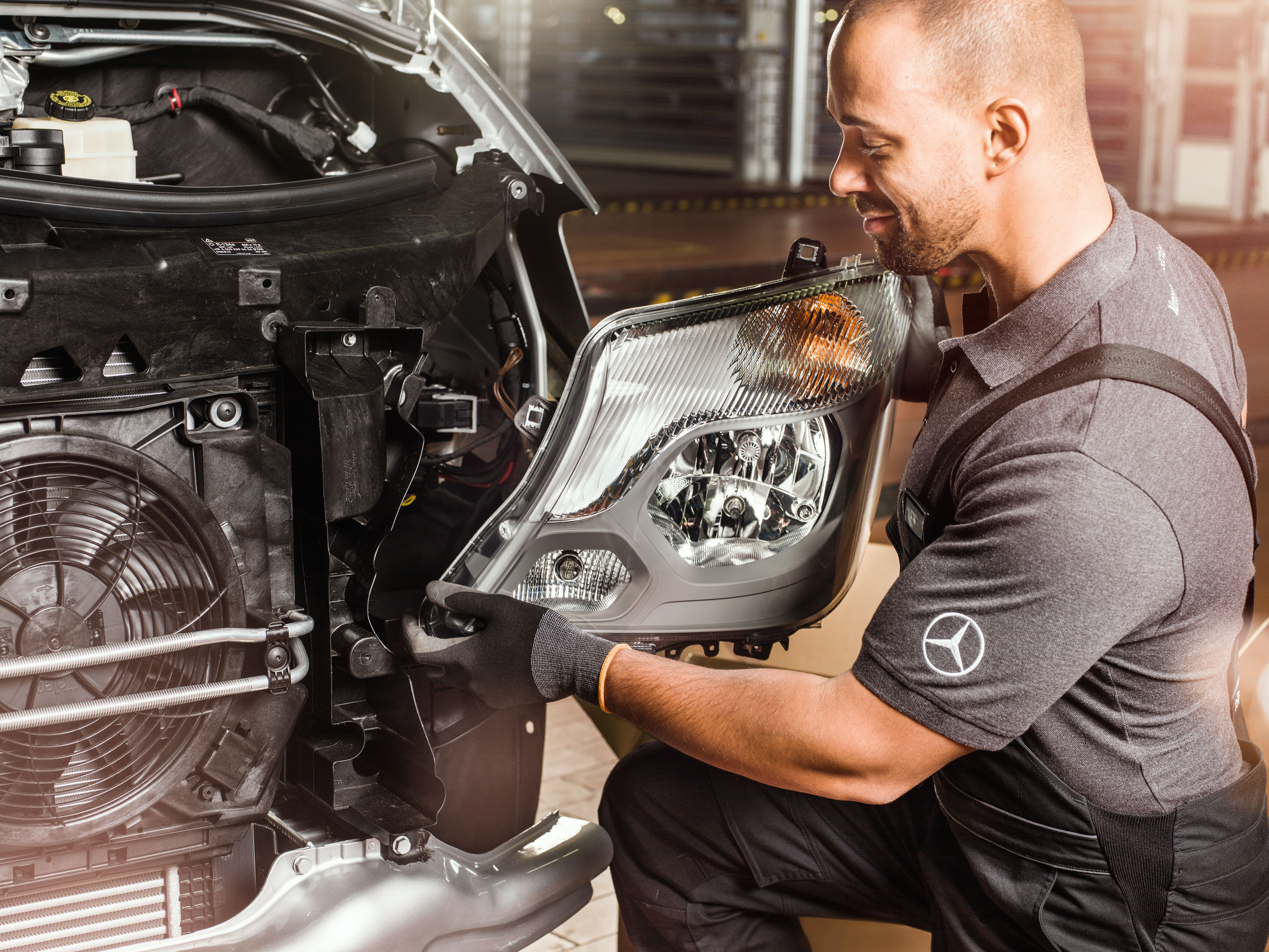 Mercedes-Benz | Transporter Qualität Original-Teile Mechaniker prüft Mercedes-Benz Original-Teile vor einem geöffneten Sprinter-Motor und gleicht sie mit dem Mercedes Ersatzteilkatalog ab.