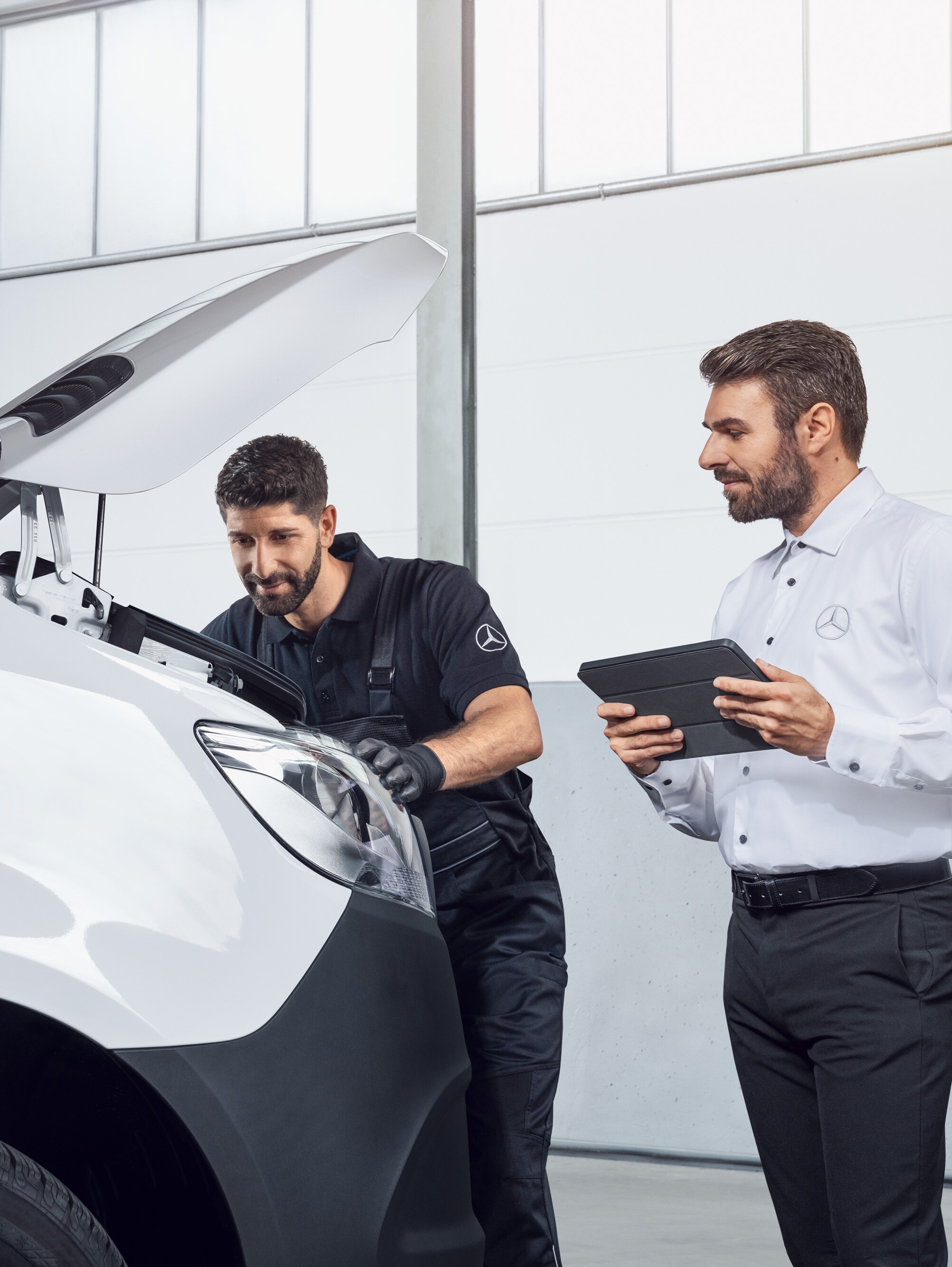 Zwei Männer mit Tablet prüfen einen Mercedes-Benz Sprinter mit offener Motorhaube, Thema: Ersatzteile Mercedes-Benz Sprinter.