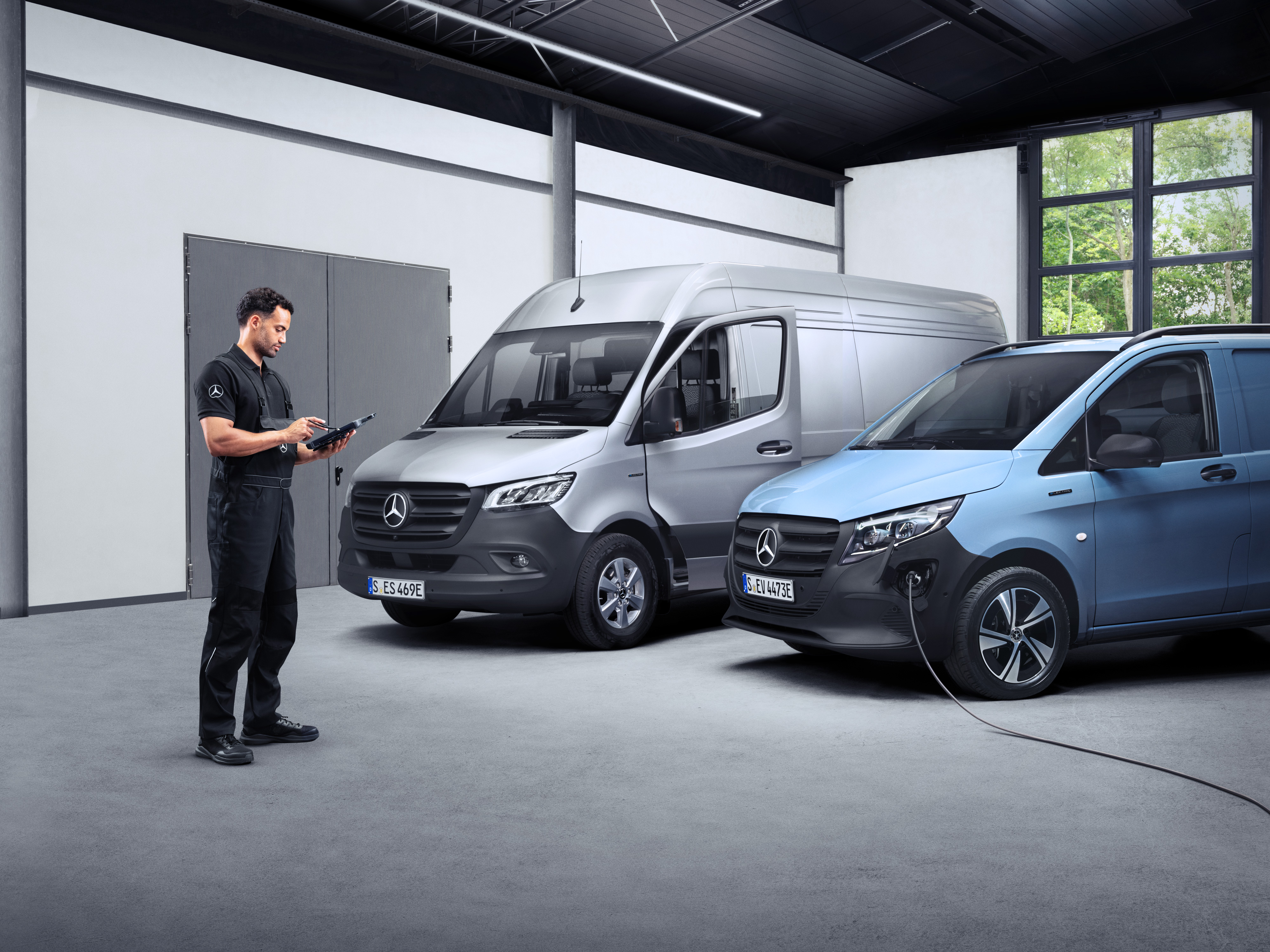 ServiceCare | Mercedes-Benz Transporter. Ein Techniker steht vor Mercedes-Benz Transportern in einer Halle – abgesichert mit dem Mercedes Service Paket.